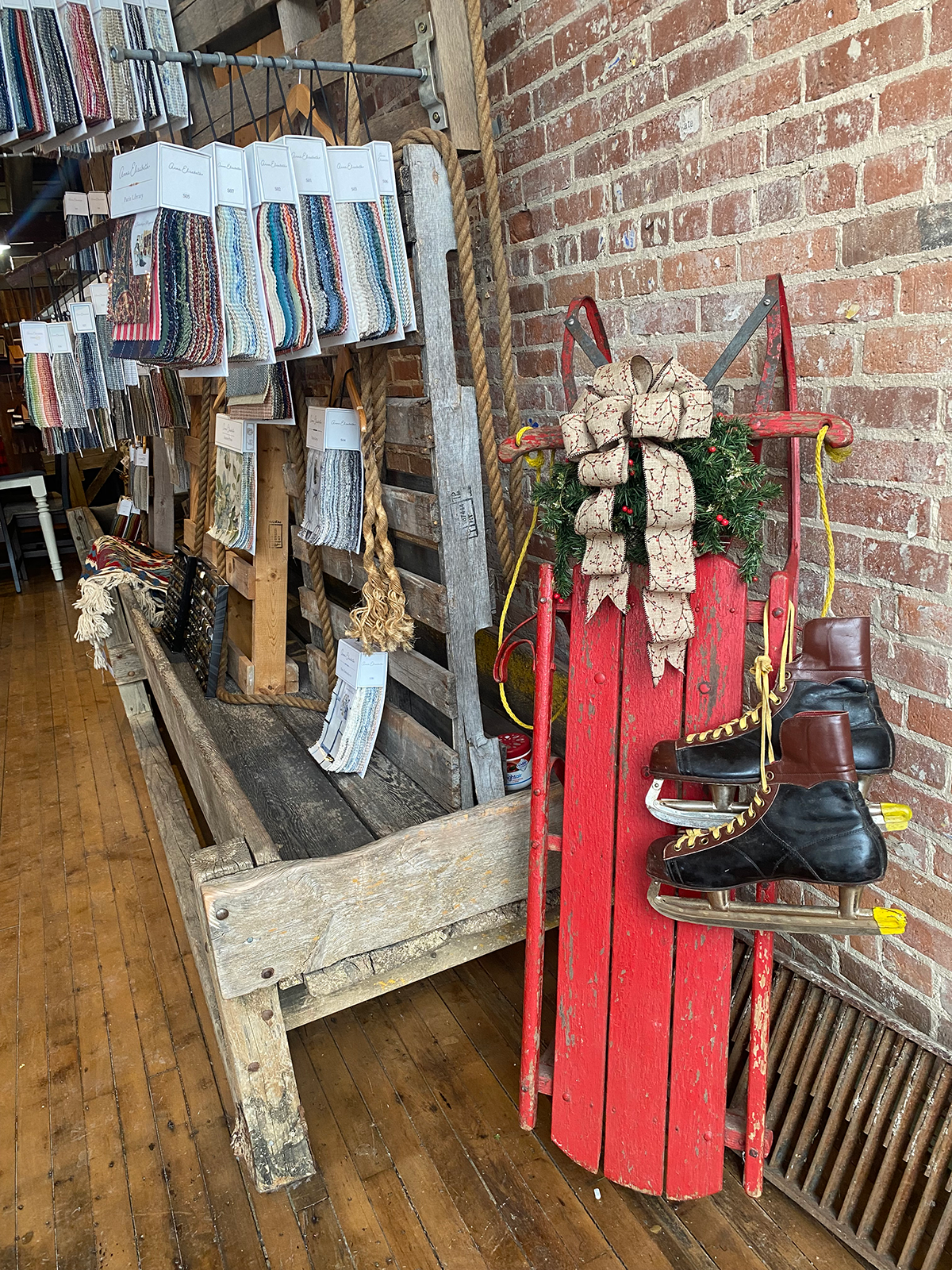 Wooden sled and ice skates leaning against brick wall.