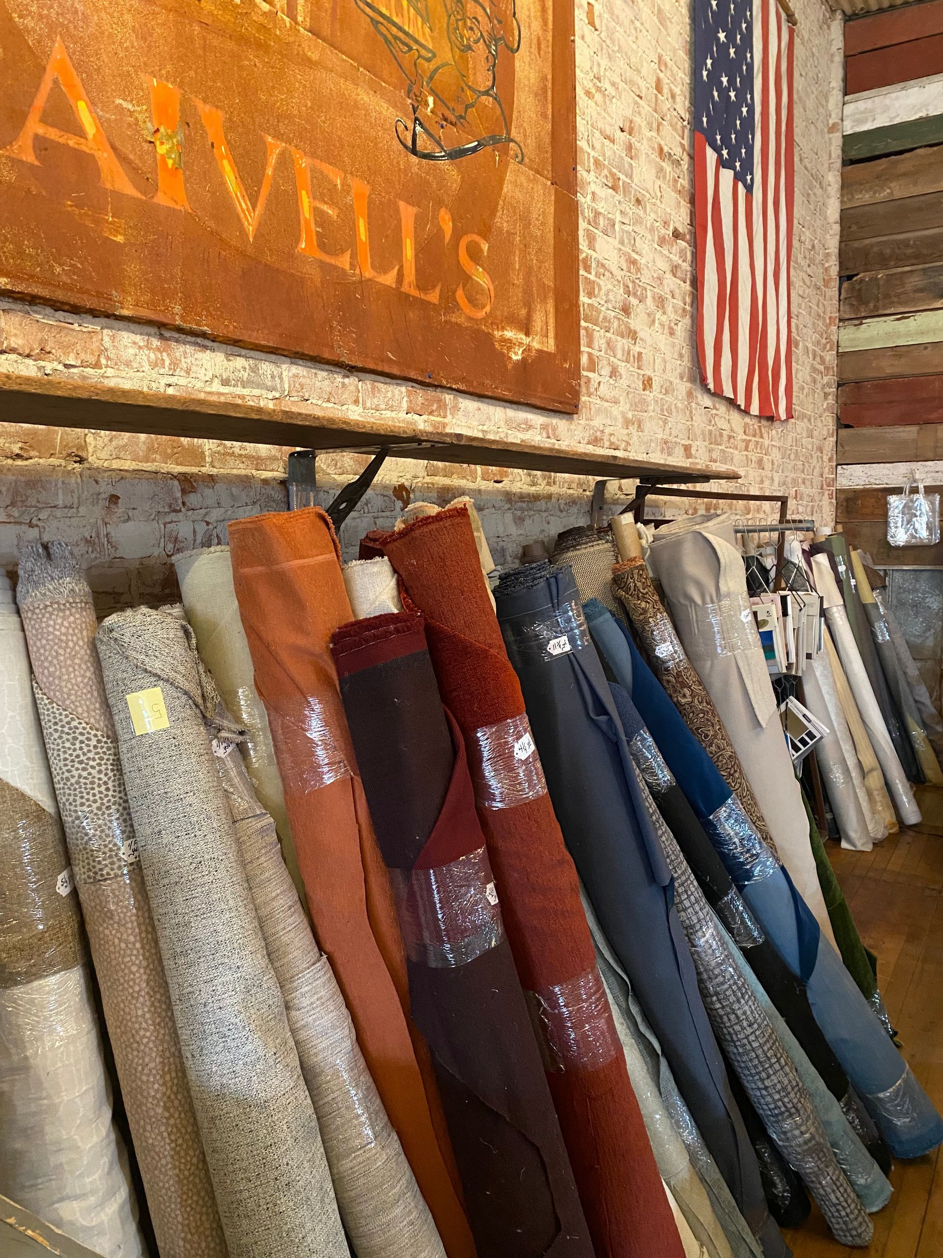 A bunch of rolls of fabric are hanging on a rack in a store.