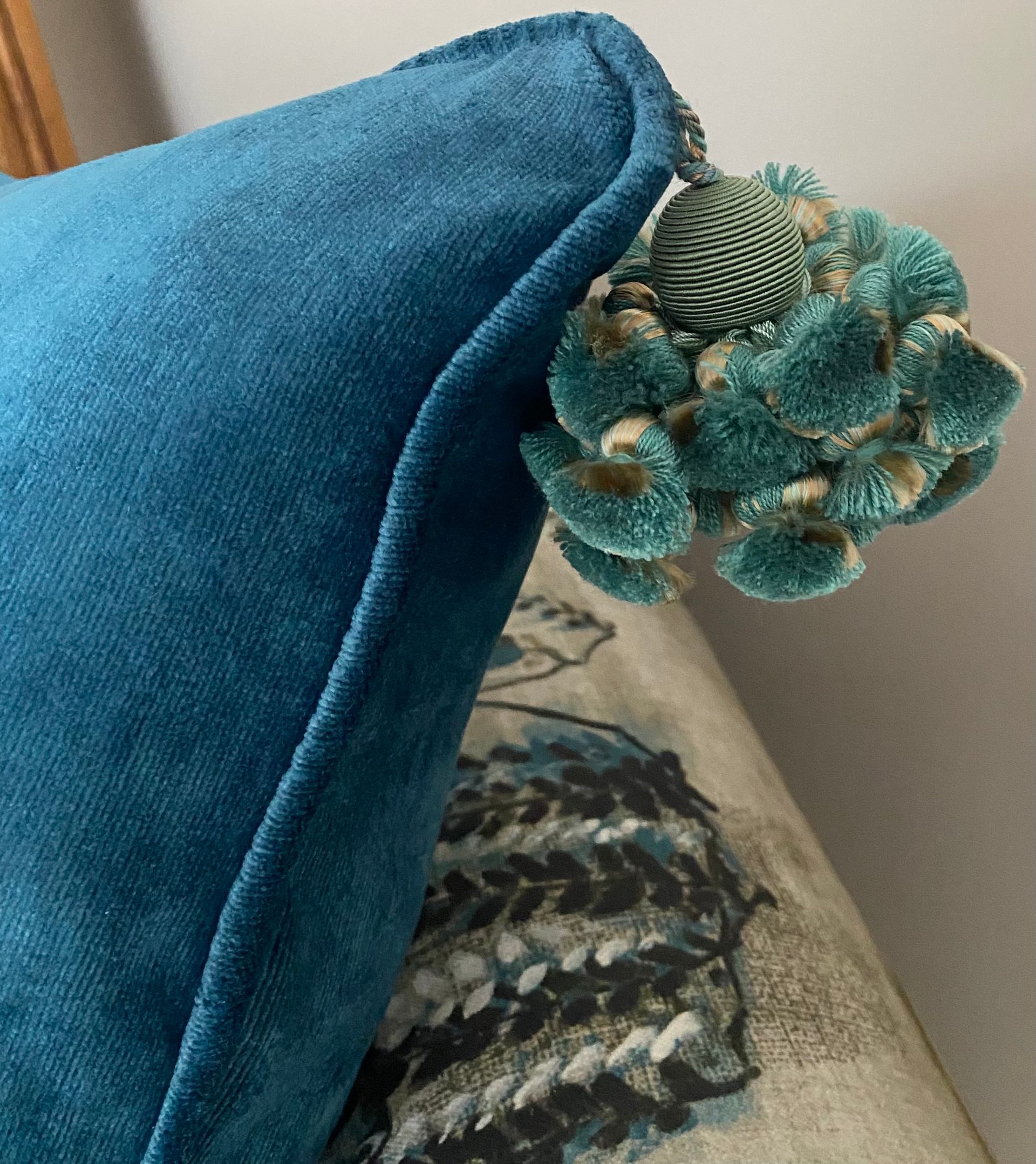 A close up of a blue pillow with a tassel on it