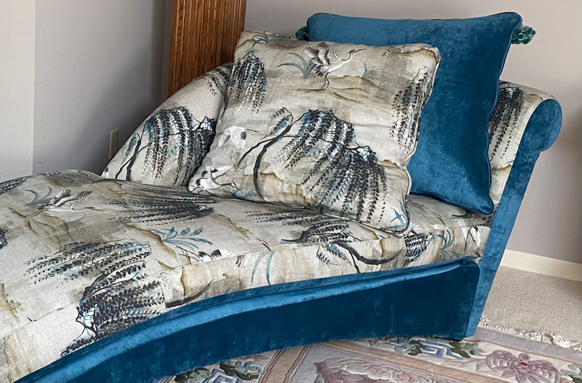 A chaise lounge with blue pillows on it is sitting on a rug in a room.