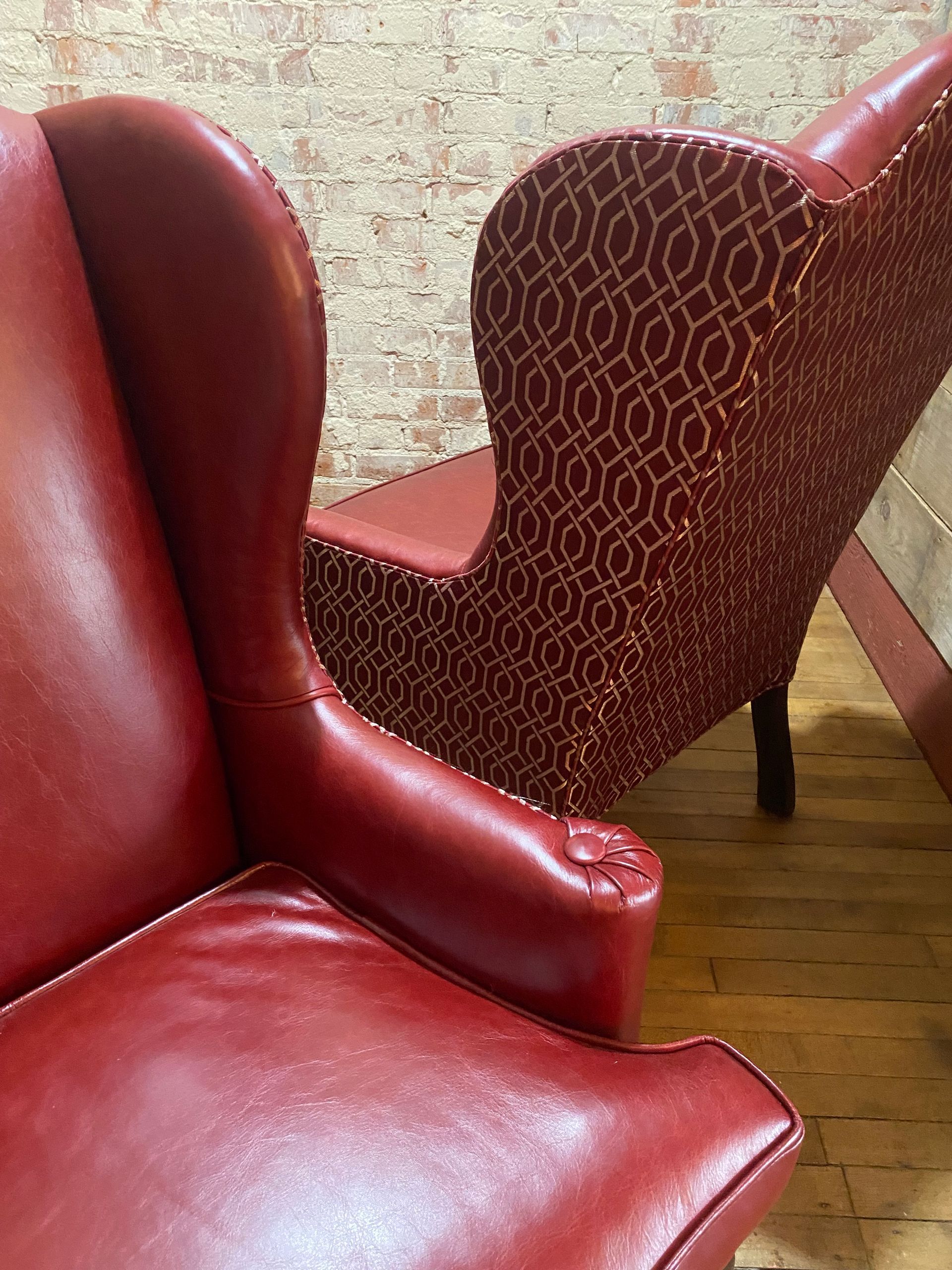 Two red chairs are sitting next to each other on a wooden floor.