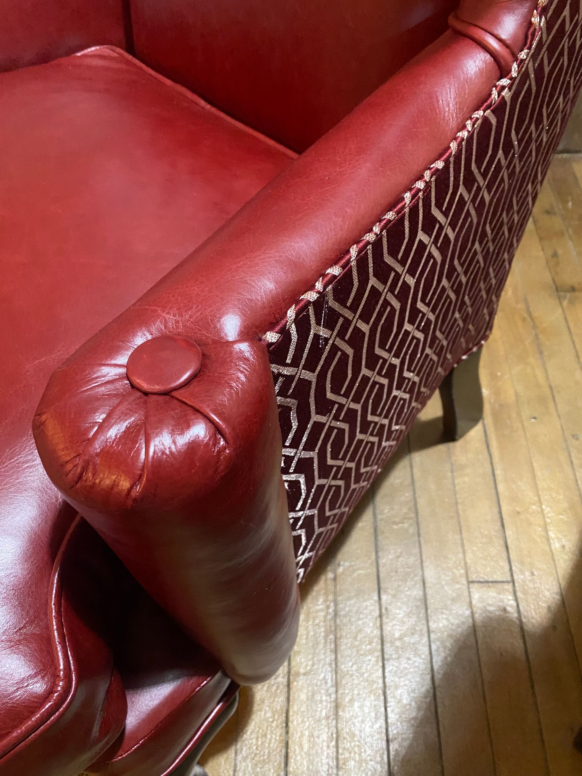 A red leather chair is sitting on a wooden floor