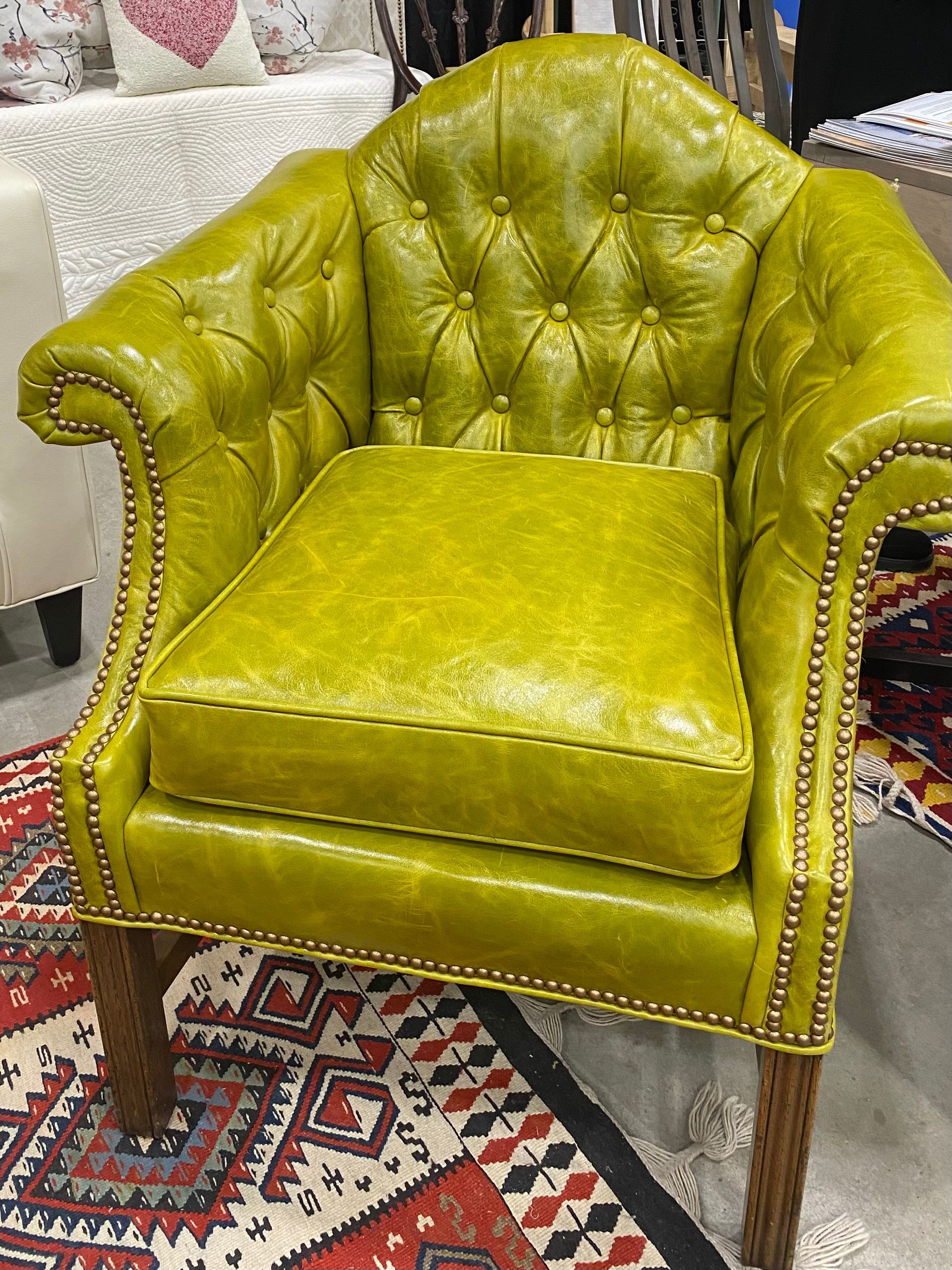 A green leather chair is sitting on top of a rug.