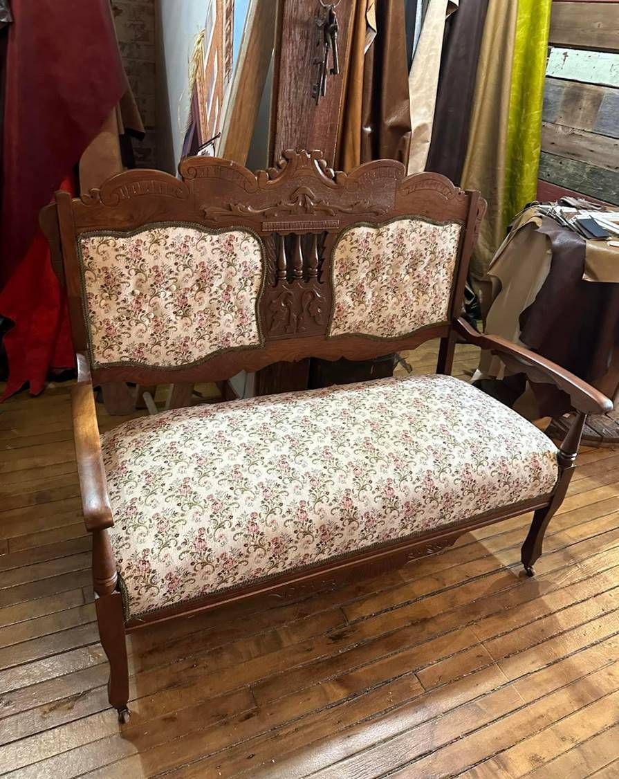 A wooden bench with a floral cushion is sitting on a wooden floor in a room.