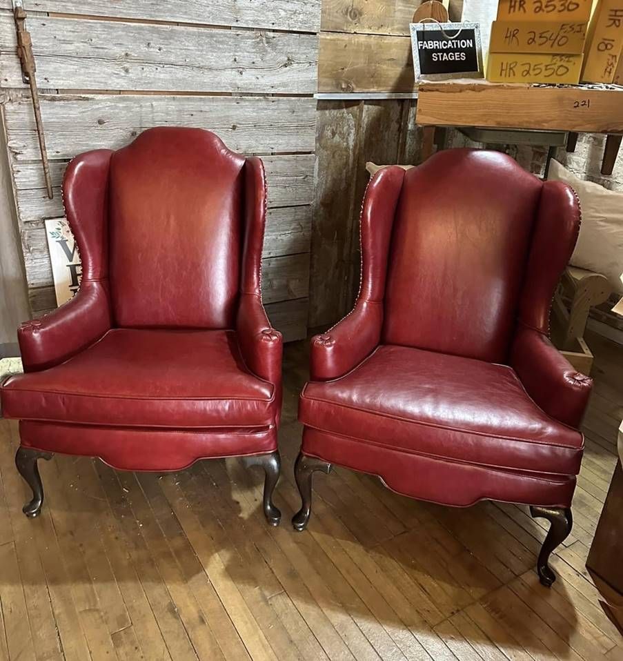Two red leather chairs are sitting next to each other on a wooden floor.