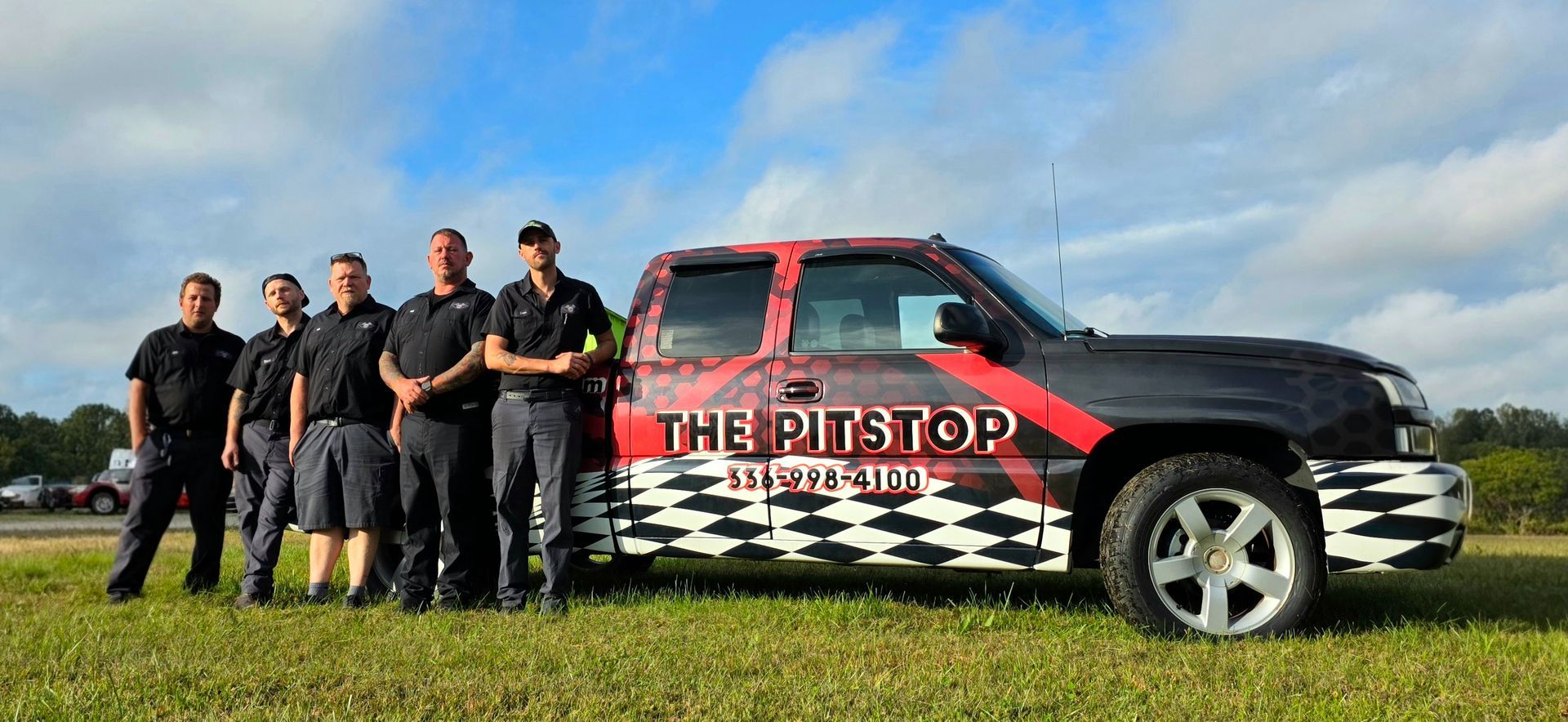 Group of men standing in front of a truck with logo