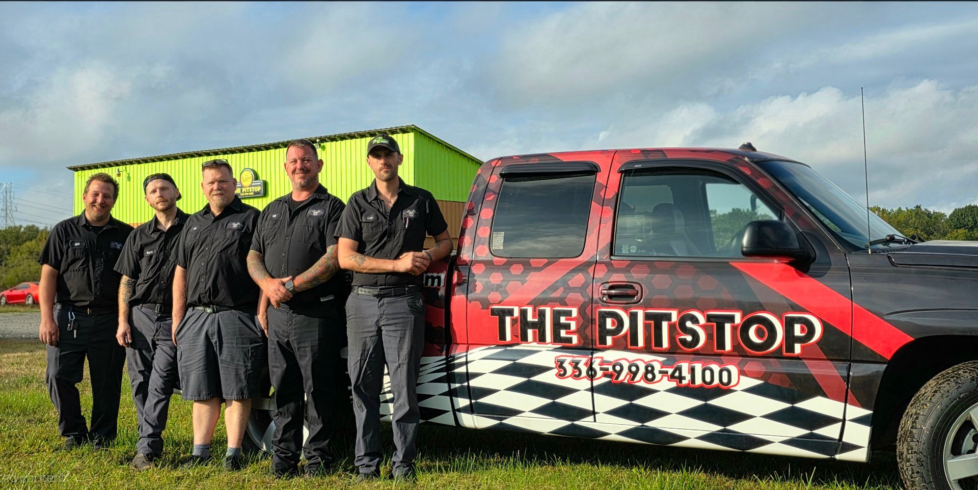 Five men in uniform pose next to a truck with