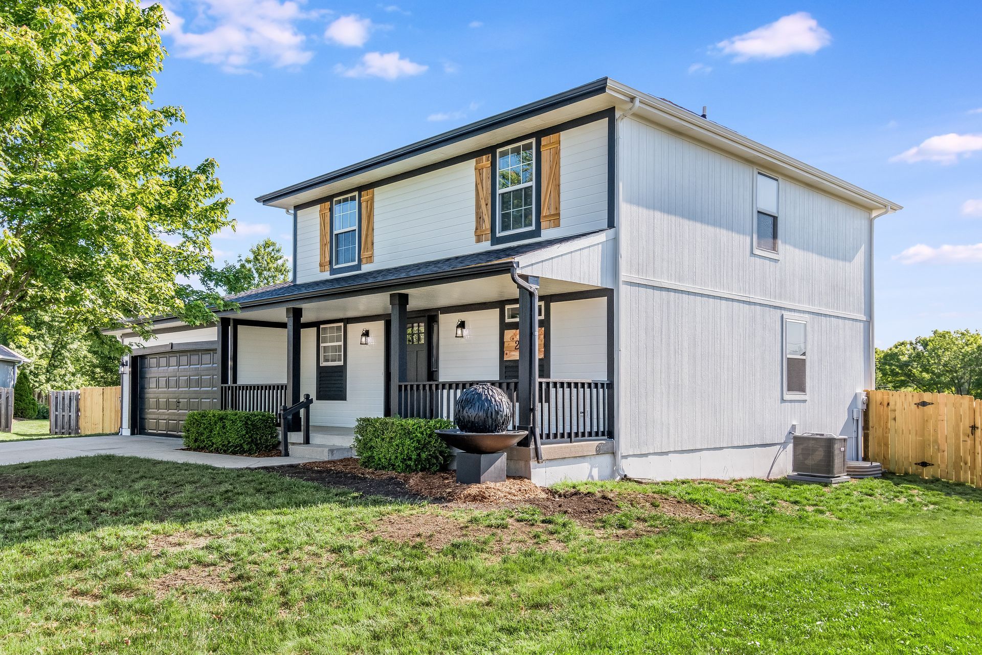 A white house with a porch and a large lawn in front of it.