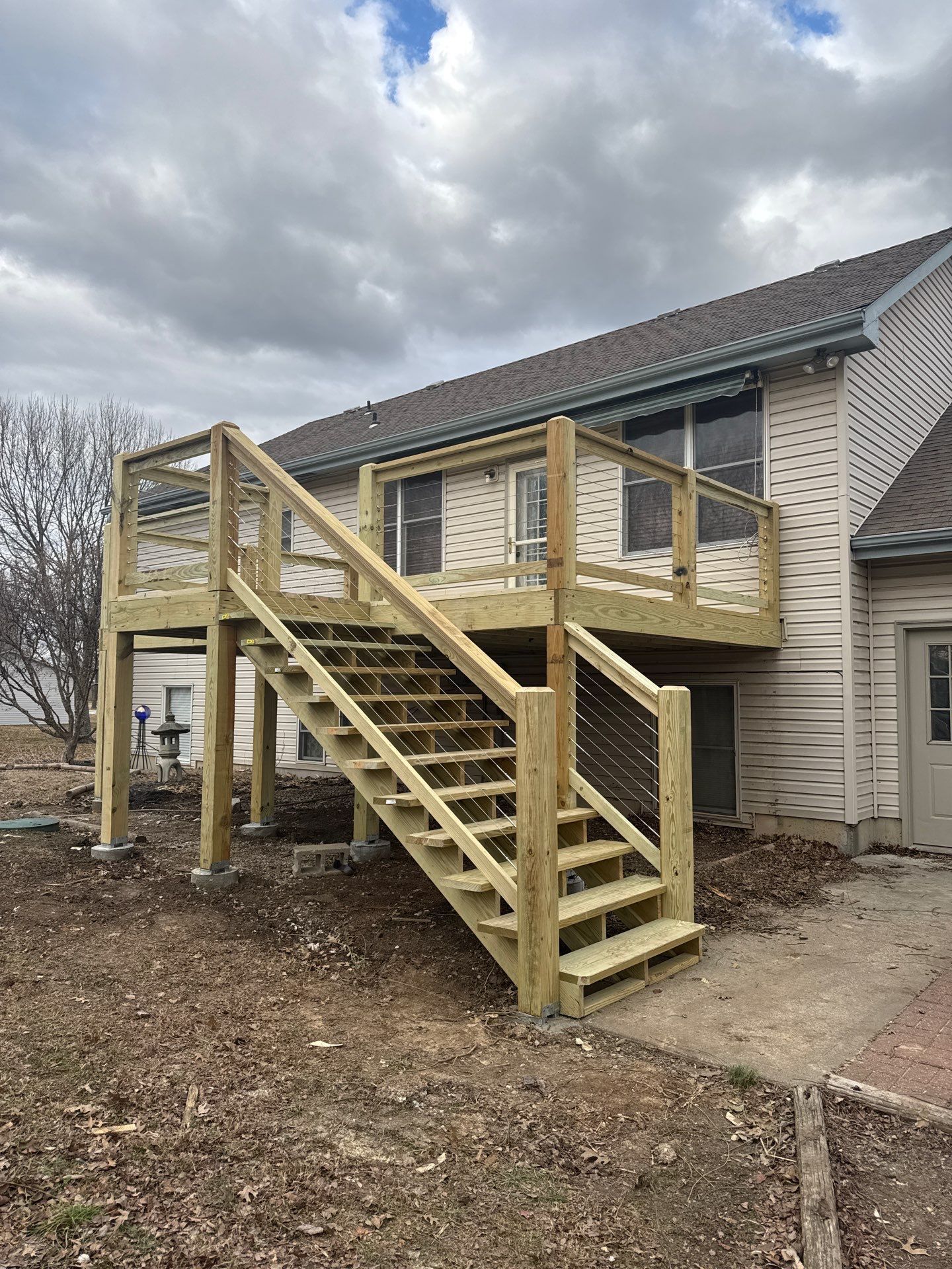 A wooden deck with stairs leading up to it is in the back of a house.