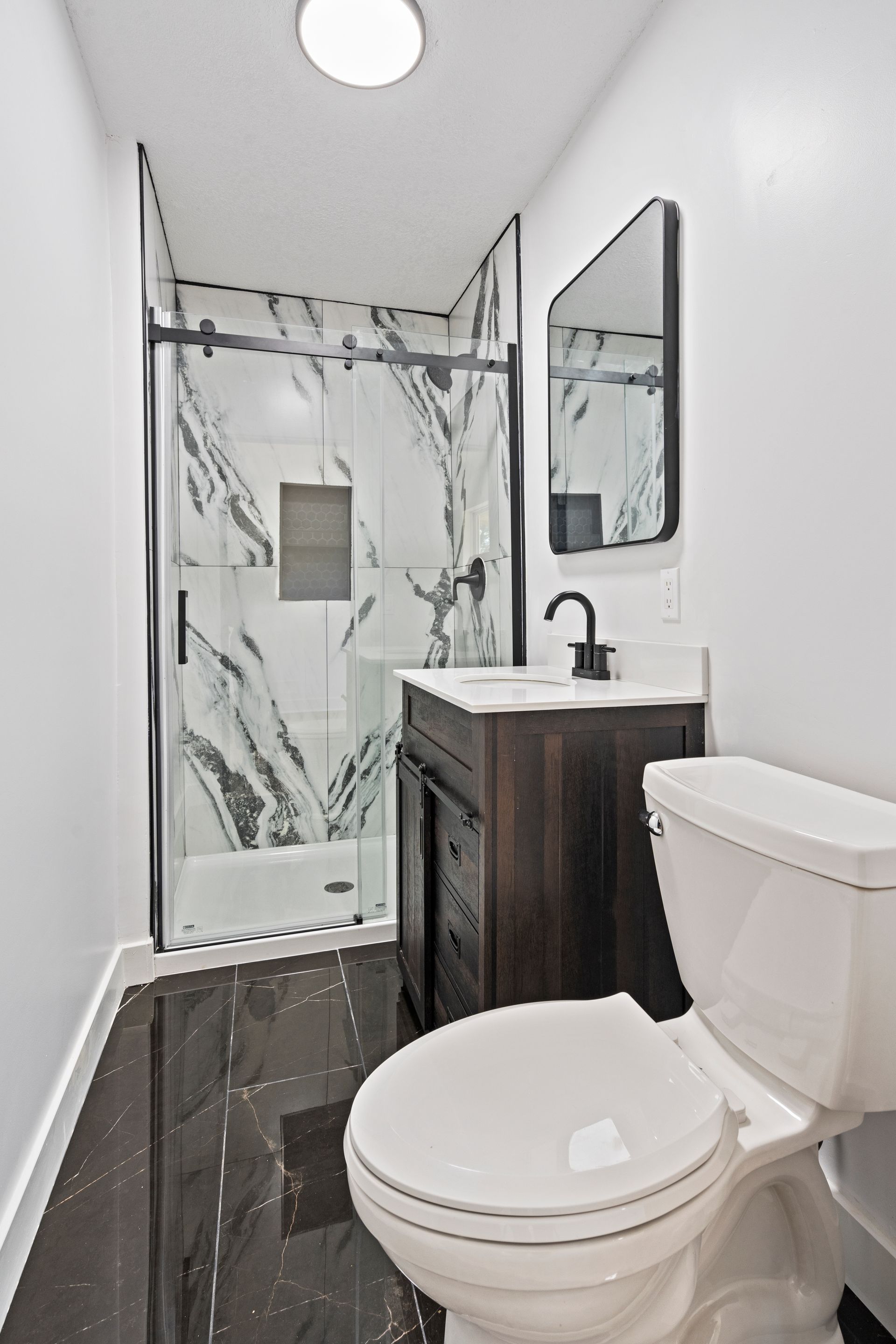 A bathroom with a toilet , sink and shower.