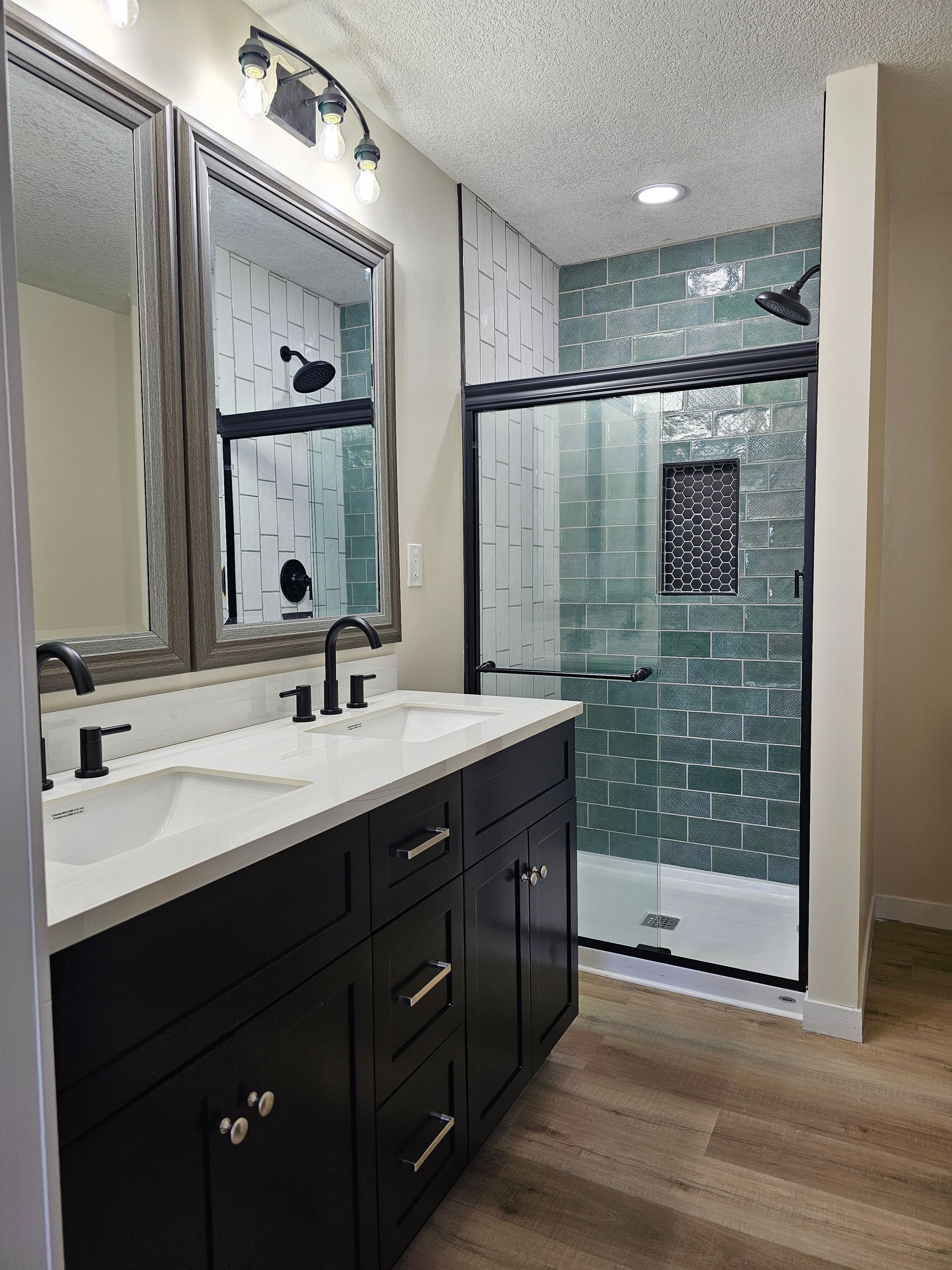A bathroom with two sinks , a shower and two mirrors.