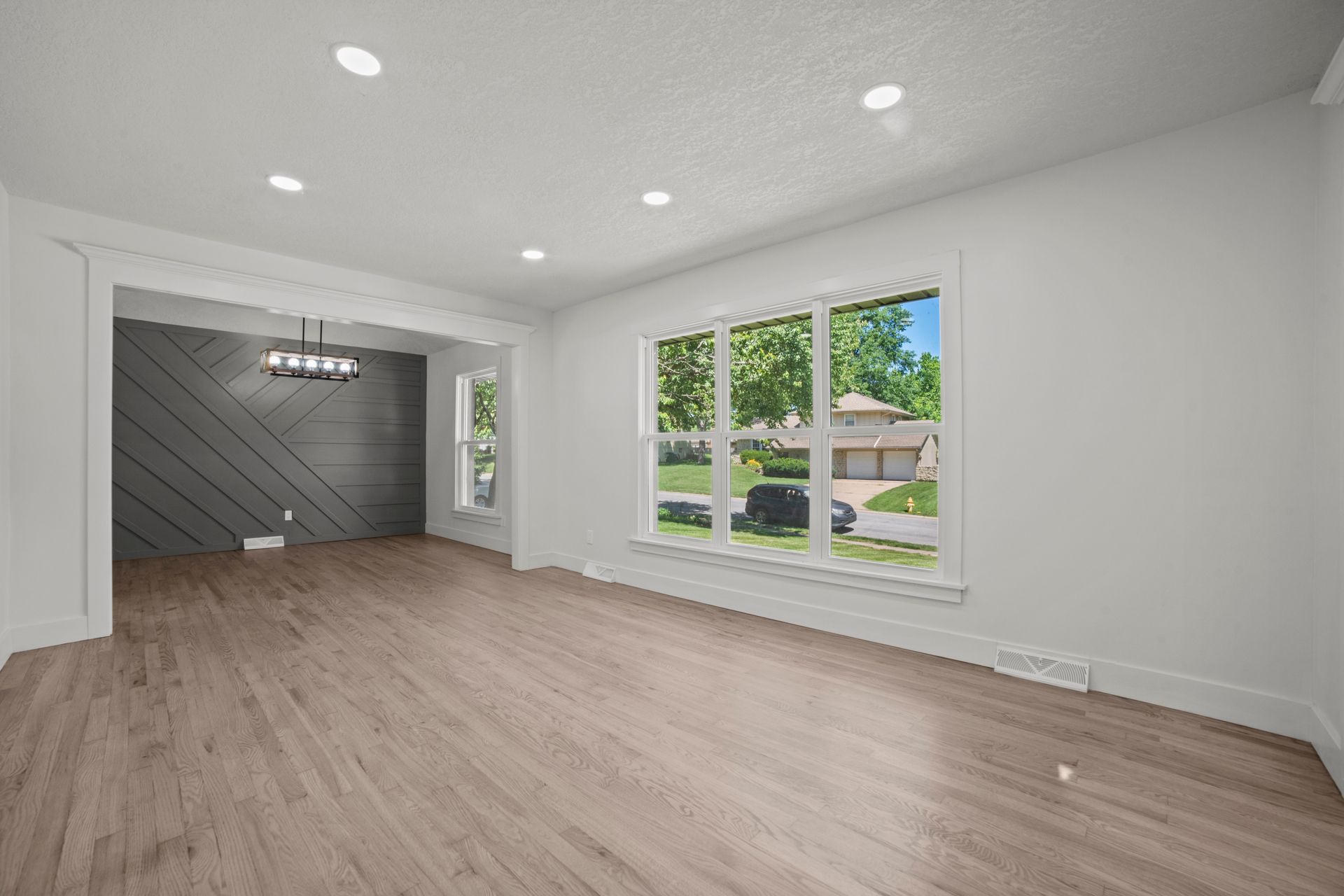 An empty living room with hardwood floors and white walls.