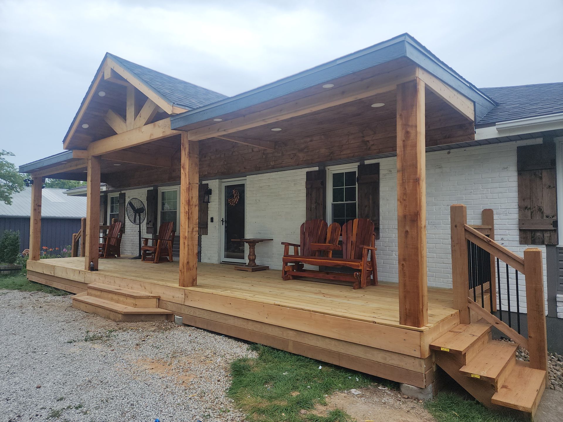 A white house with a large wooden porch and stairs.