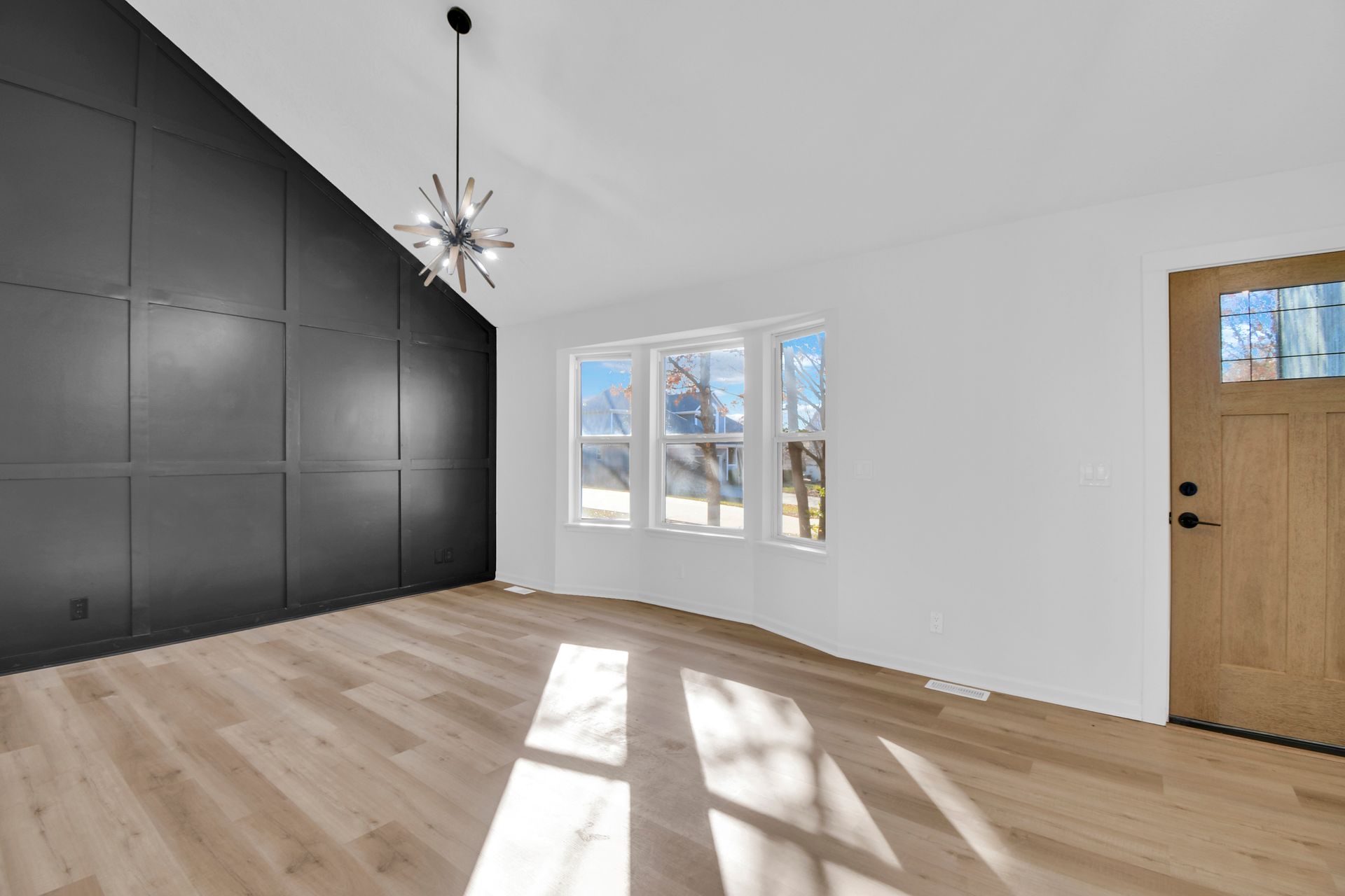 An empty living room with hardwood floors and a vaulted ceiling.