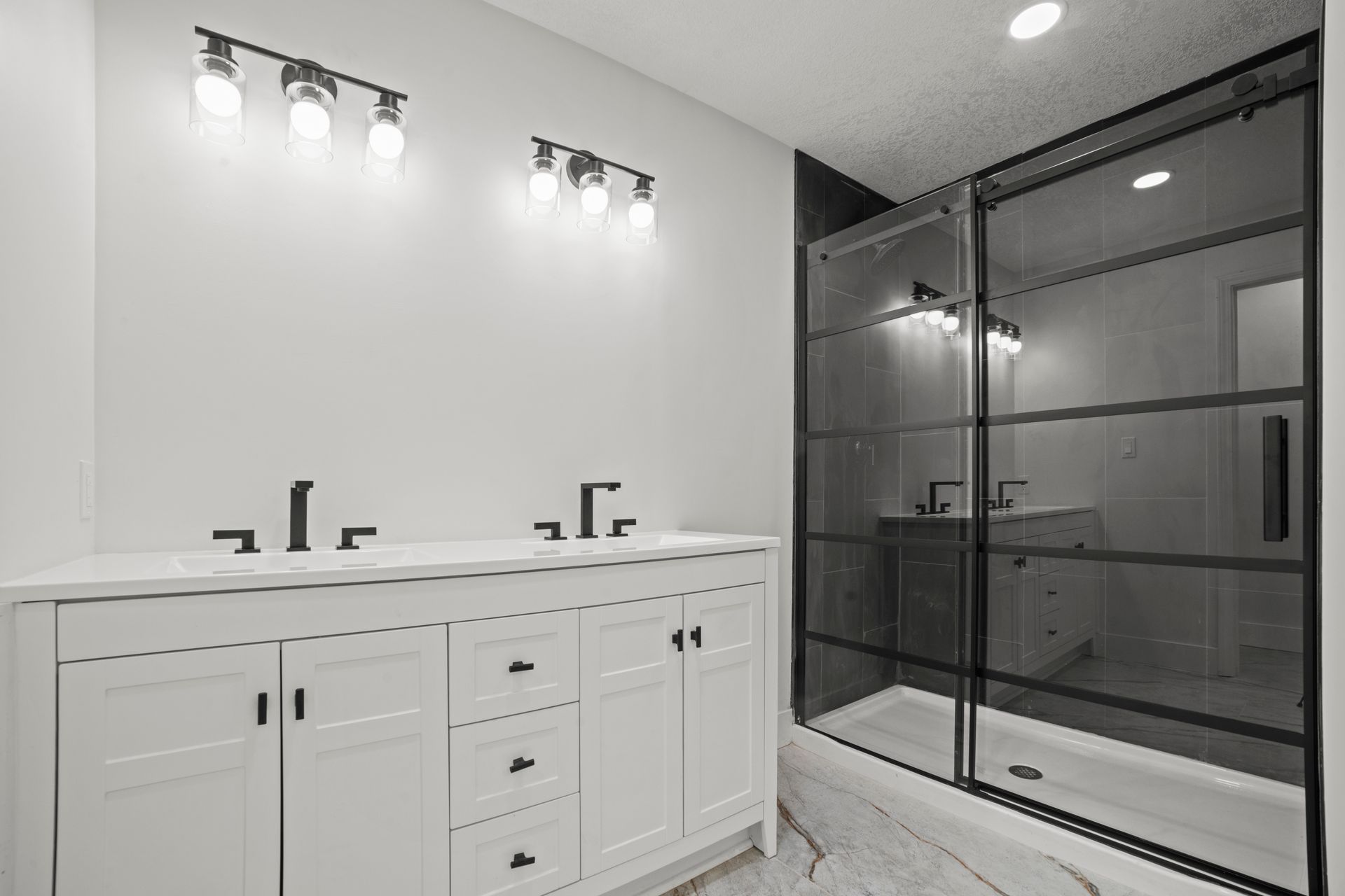A bathroom with two sinks , a shower and a mirror.