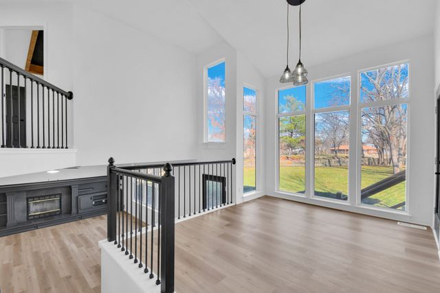 An empty living room with hardwood floors and lots of windows.