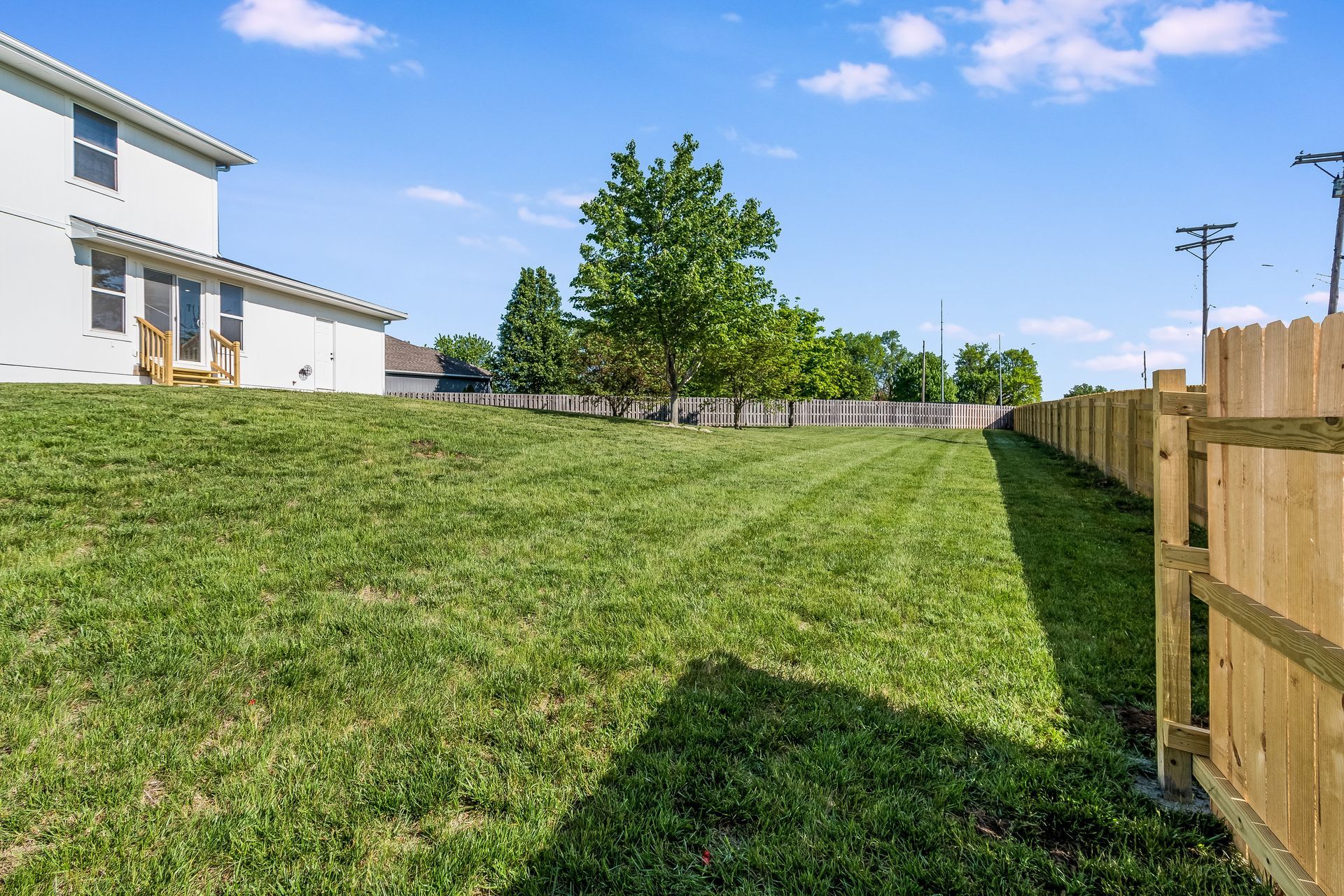 A backyard with a wooden fence and a house in the background.