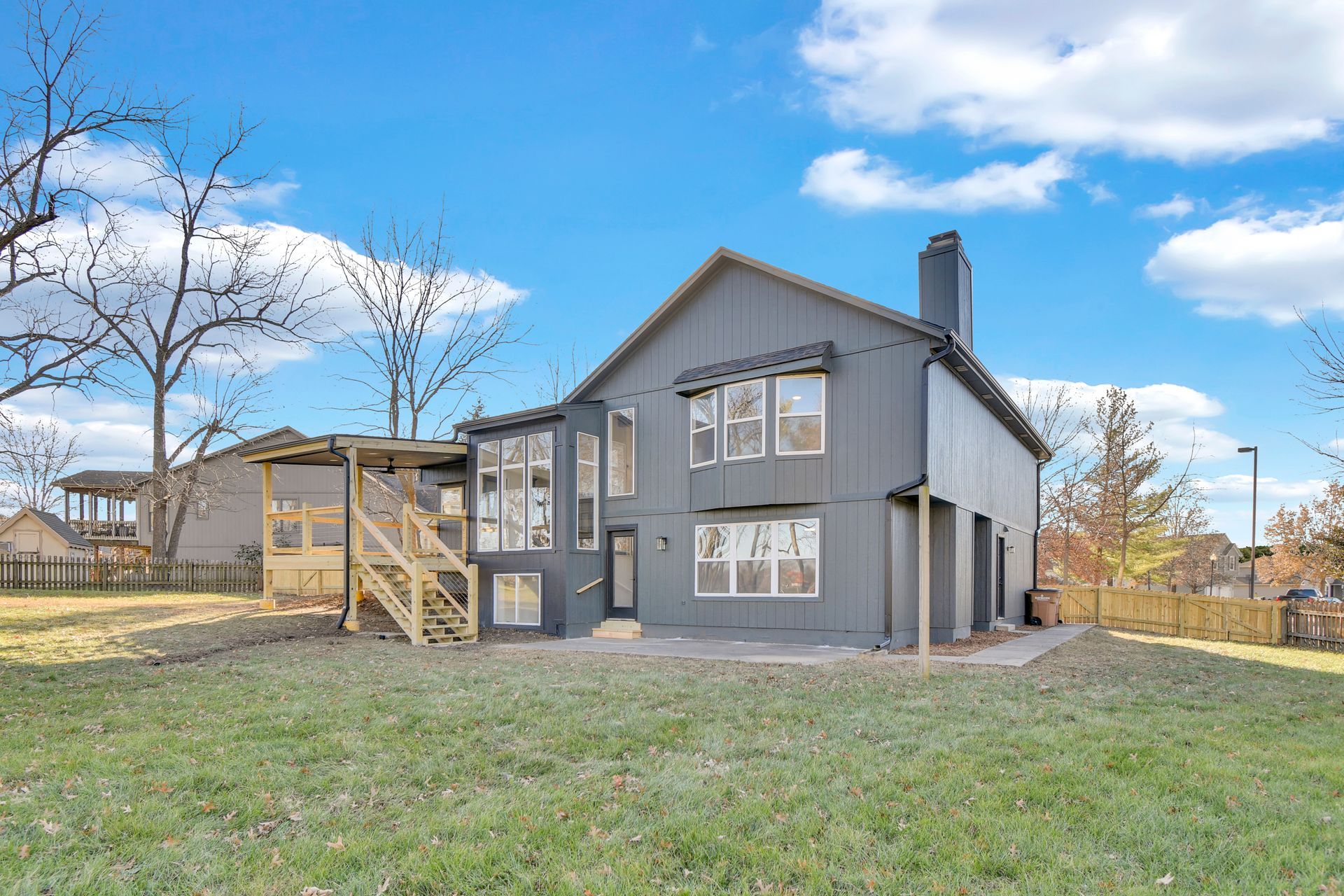 A large gray house with a lot of windows is sitting on top of a lush green lawn.