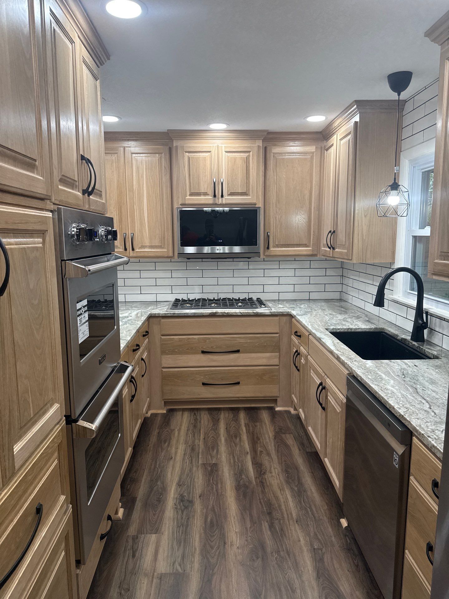 A kitchen with wooden cabinets , granite counter tops , stainless steel appliances and a sink.
