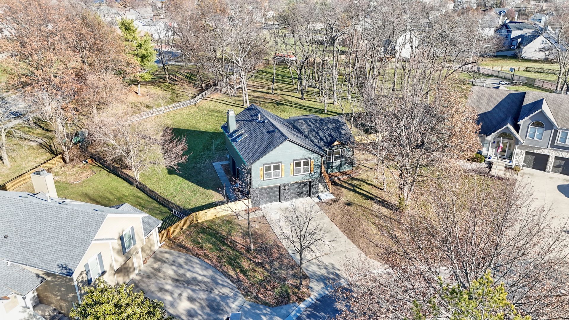 An aerial view of a house in a residential area surrounded by trees.