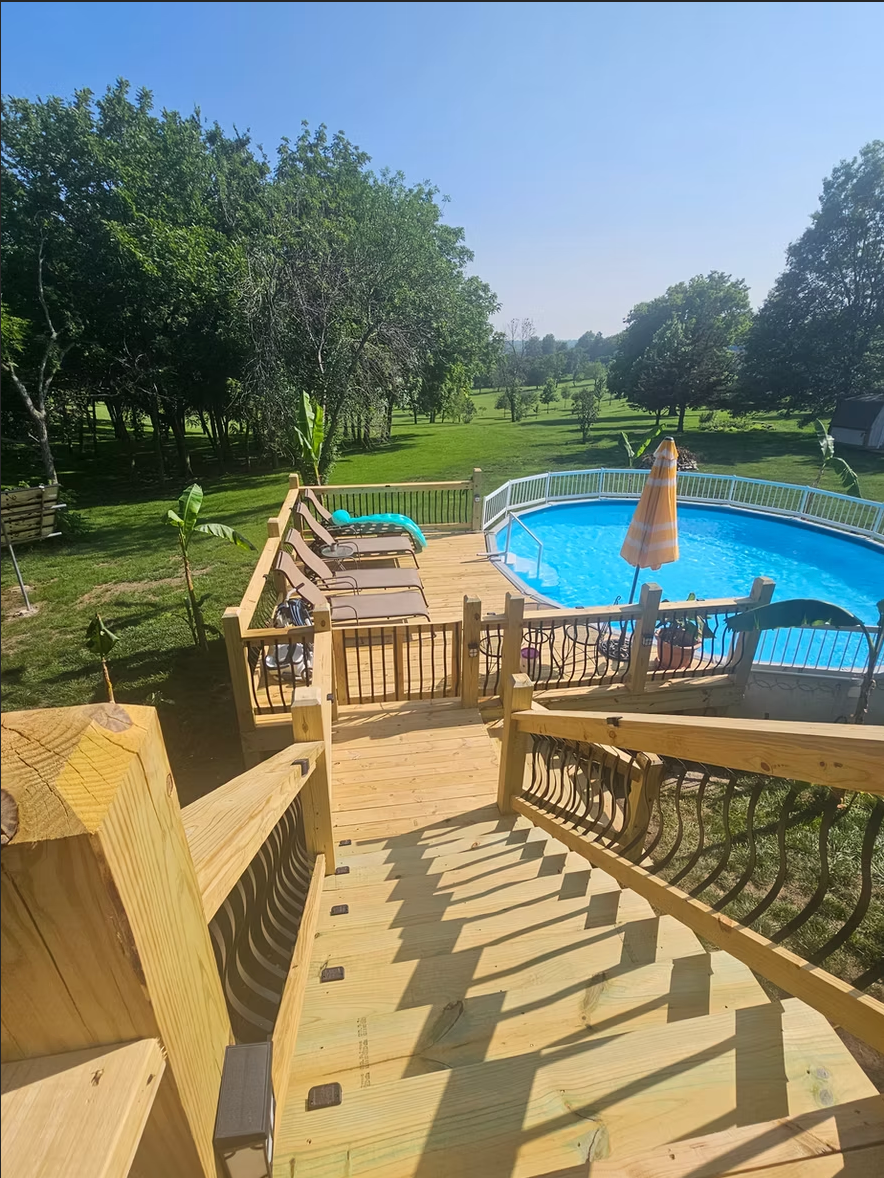 A wooden deck with a swimming pool in the background