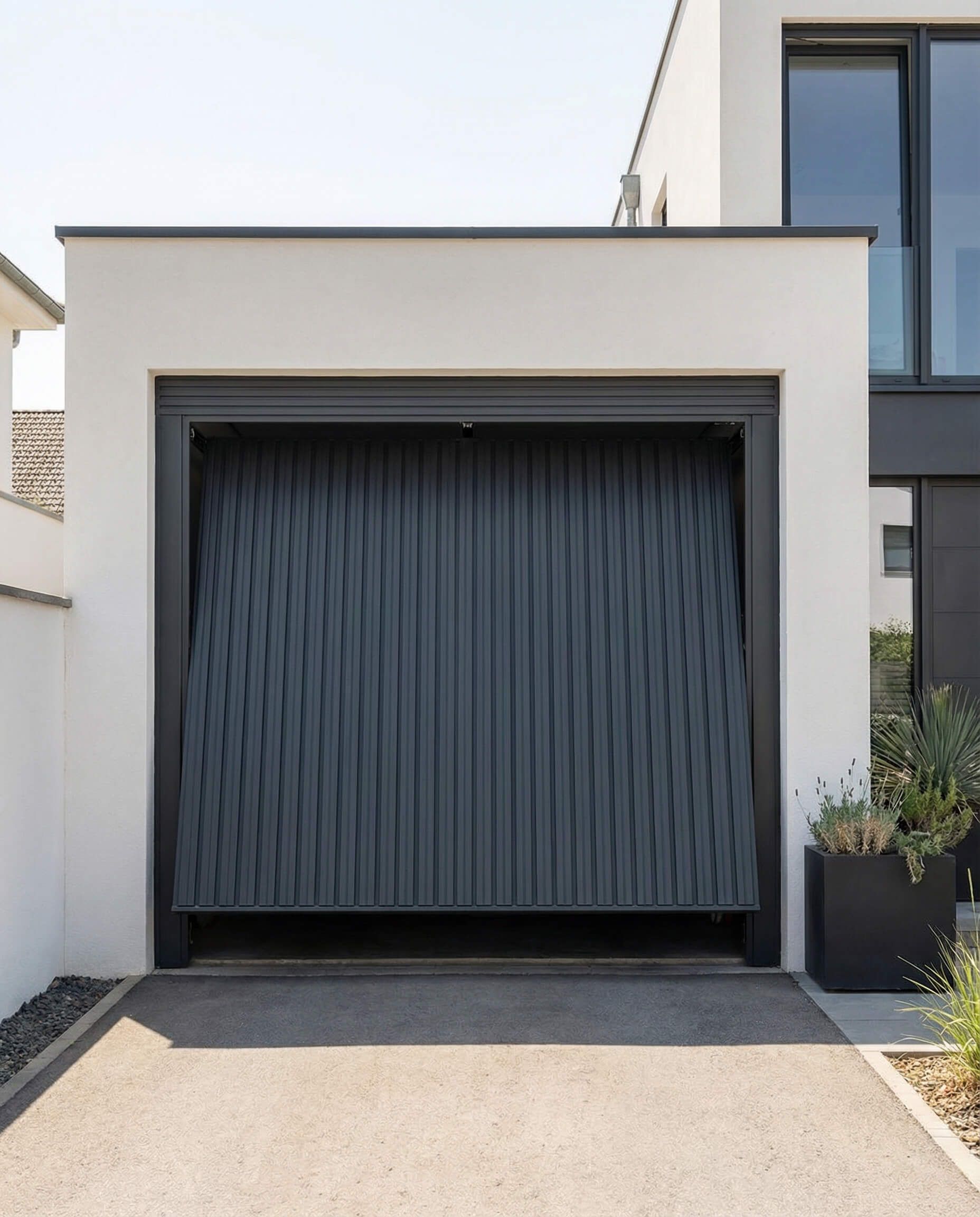 Puerta de garaje con estampado gris oscuro abierta sobre un edificio blanco.