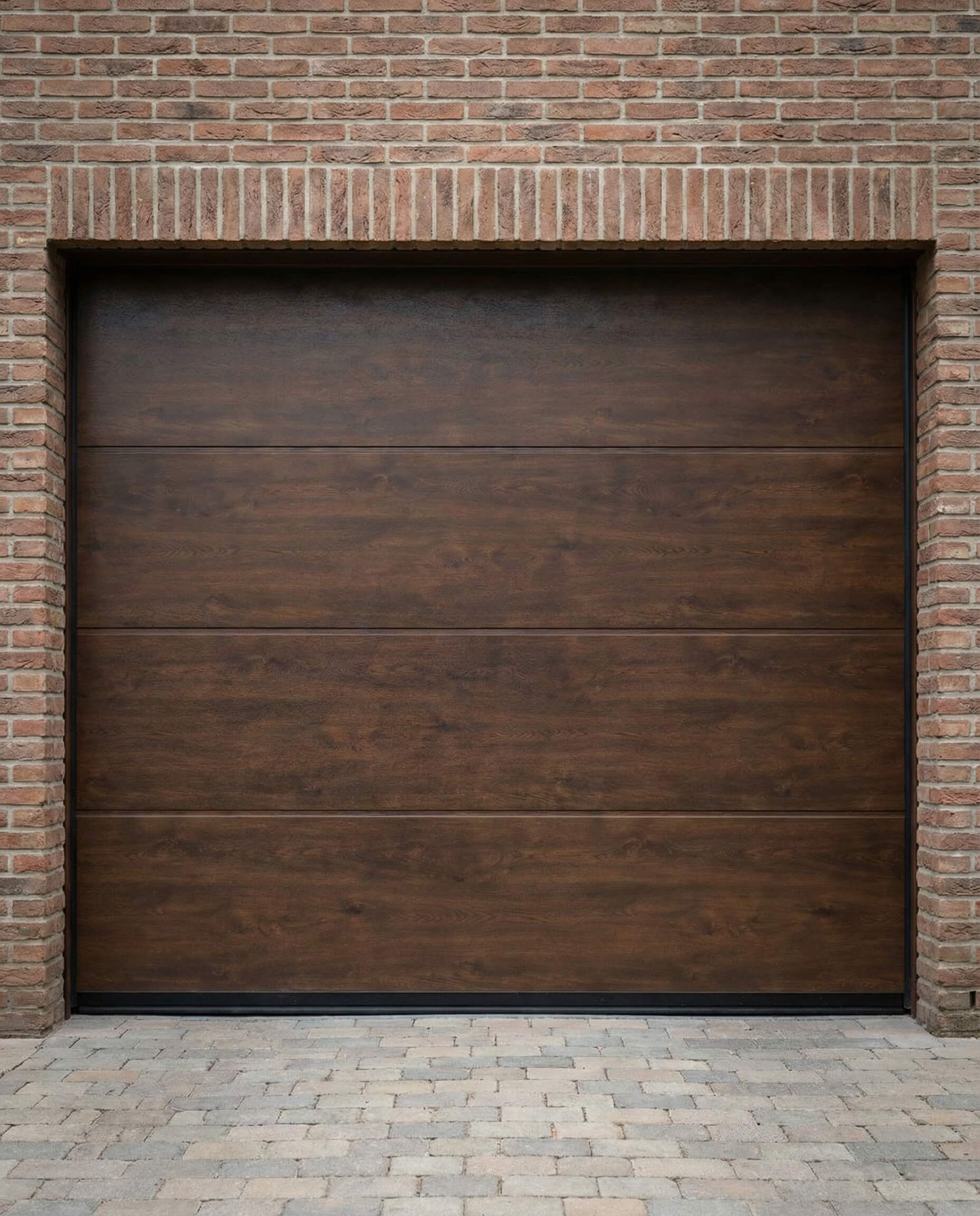 Puerta de garaje marrón colocada en un marco de ladrillo, con entrada de adoquines de ladrillo.