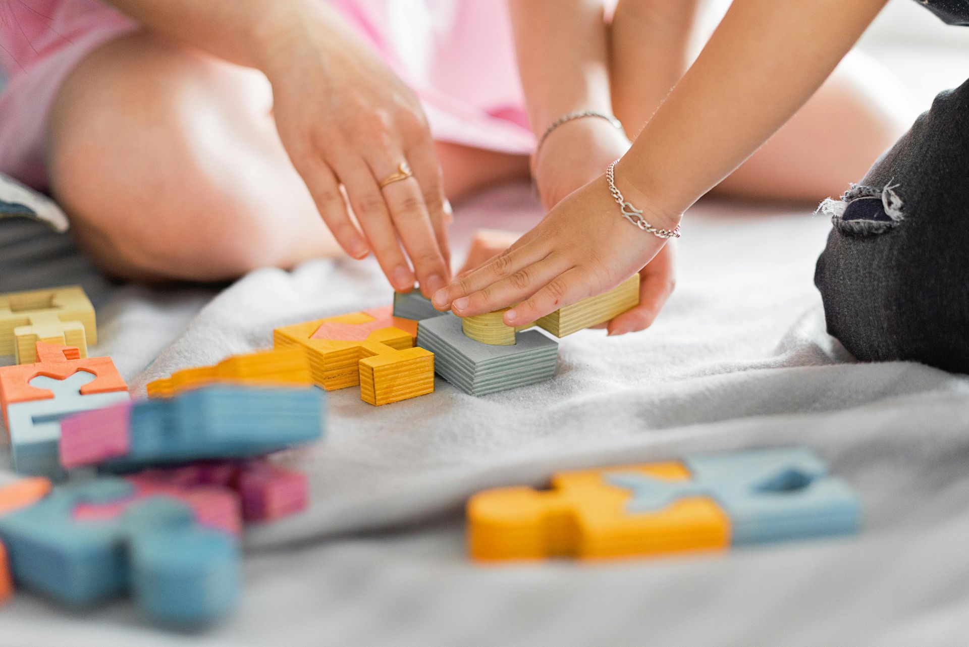 Two children are playing with wooden blocks on the floor.