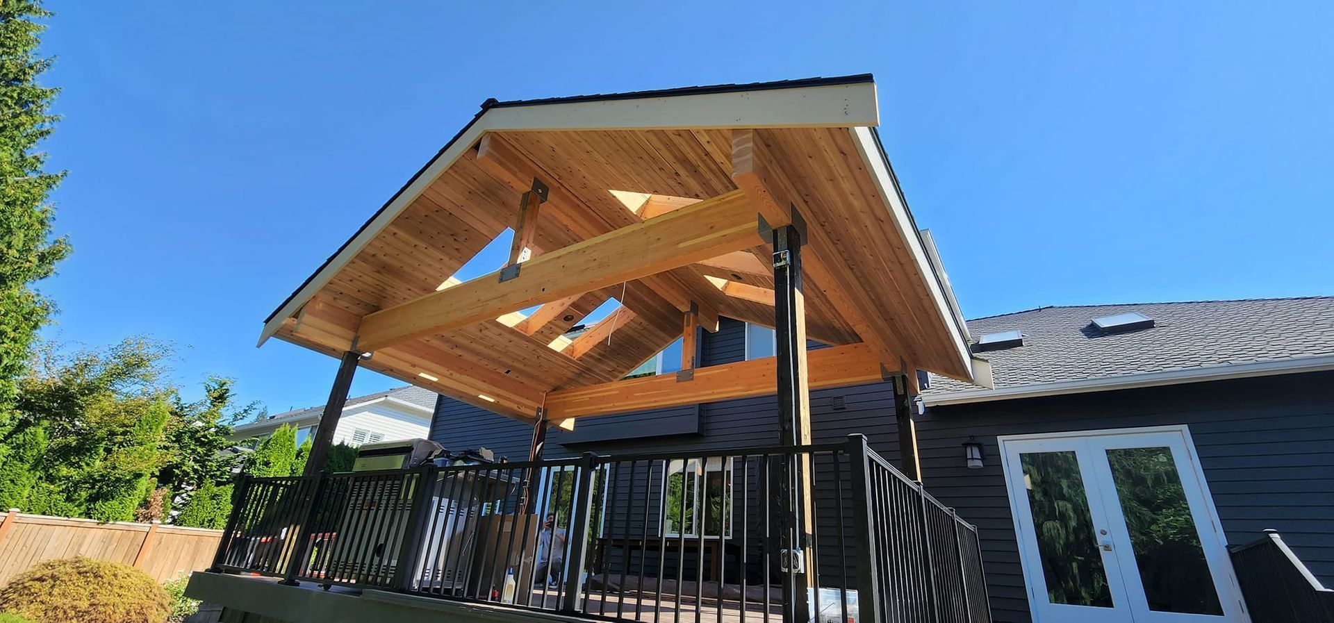 A wooden deck with a roof over it is sitting on top of a house.