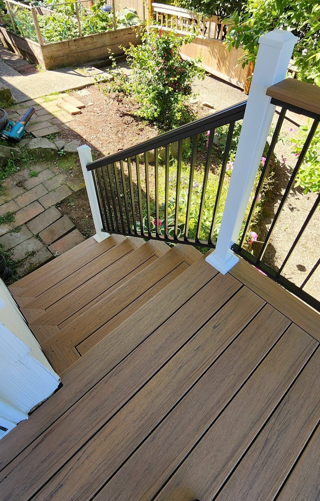 A wooden deck with stairs leading up to a garden.
