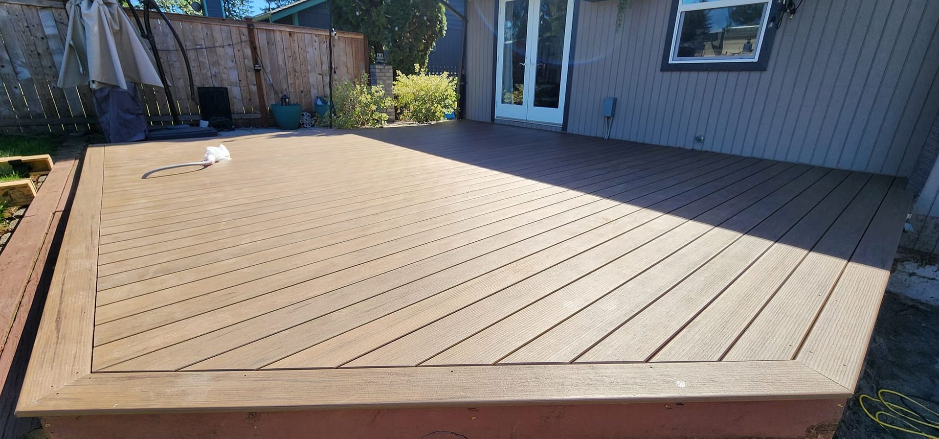 A large wooden deck is sitting in front of a house.