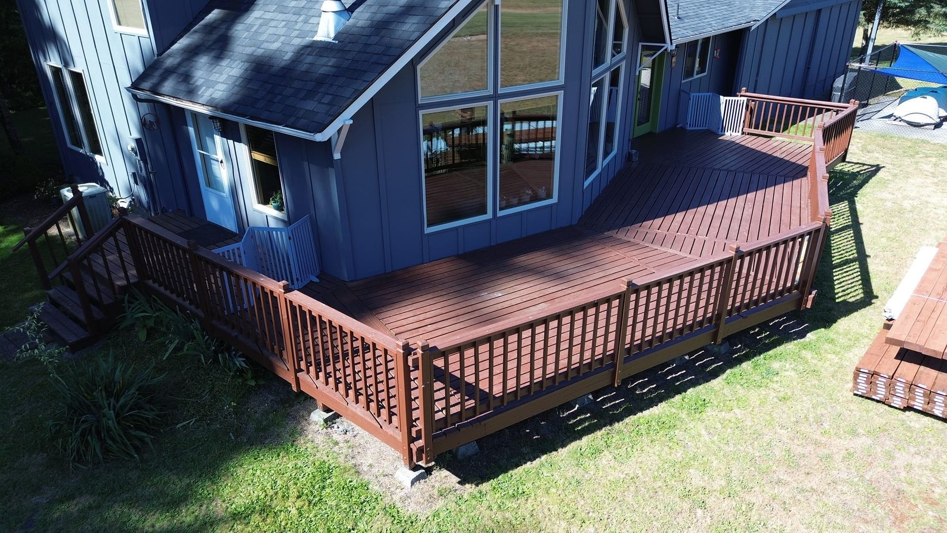 An aerial view of a wooden deck in front of a blue house.