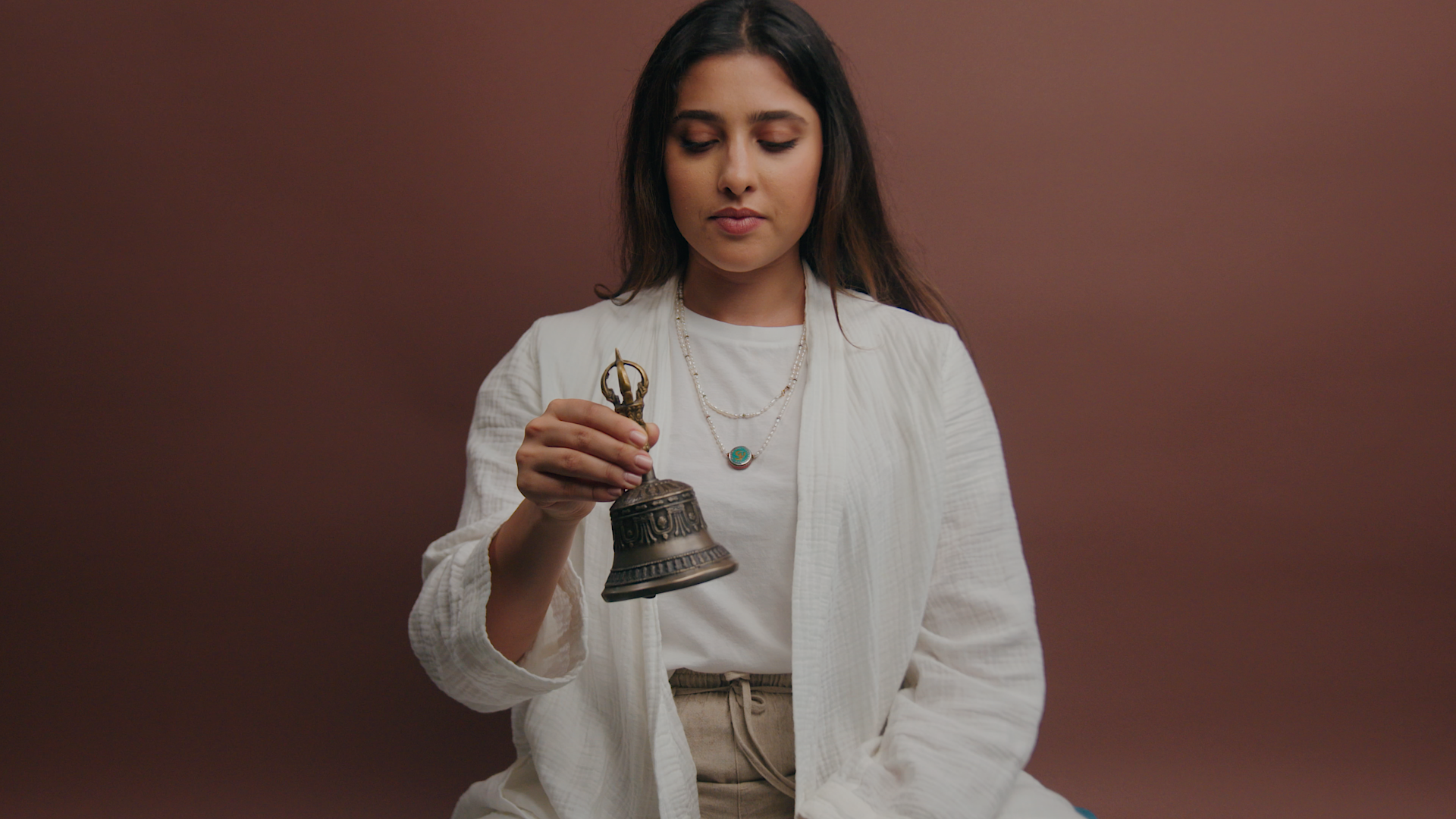A woman is sitting on a yellow couch talking to someone.