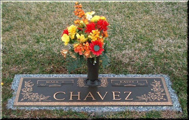A grave marker for chavez with flowers in a vase