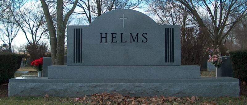 Helms grave in a cemetery with trees in the background
