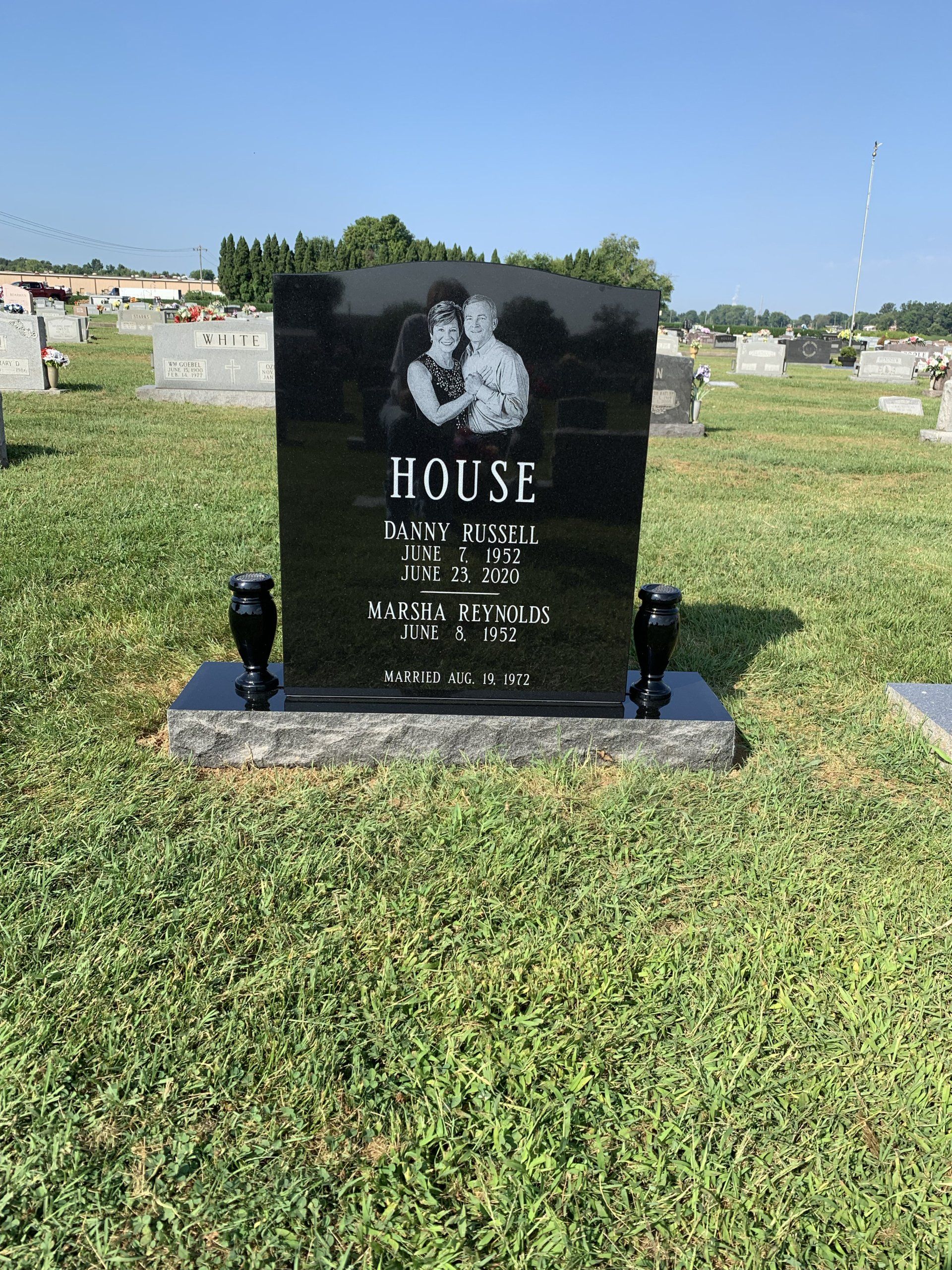 A black gravestone in a cemetery with a picture of a couple on it.