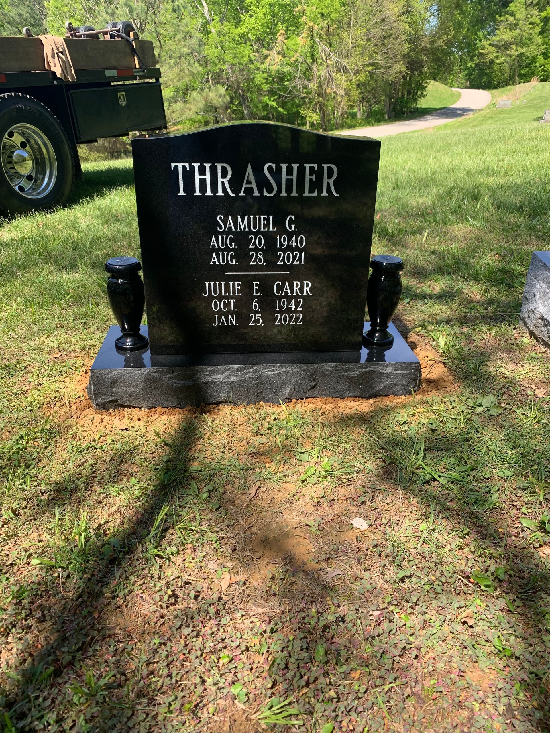 A black gravestone with the name thrasher on it in a cemetery.