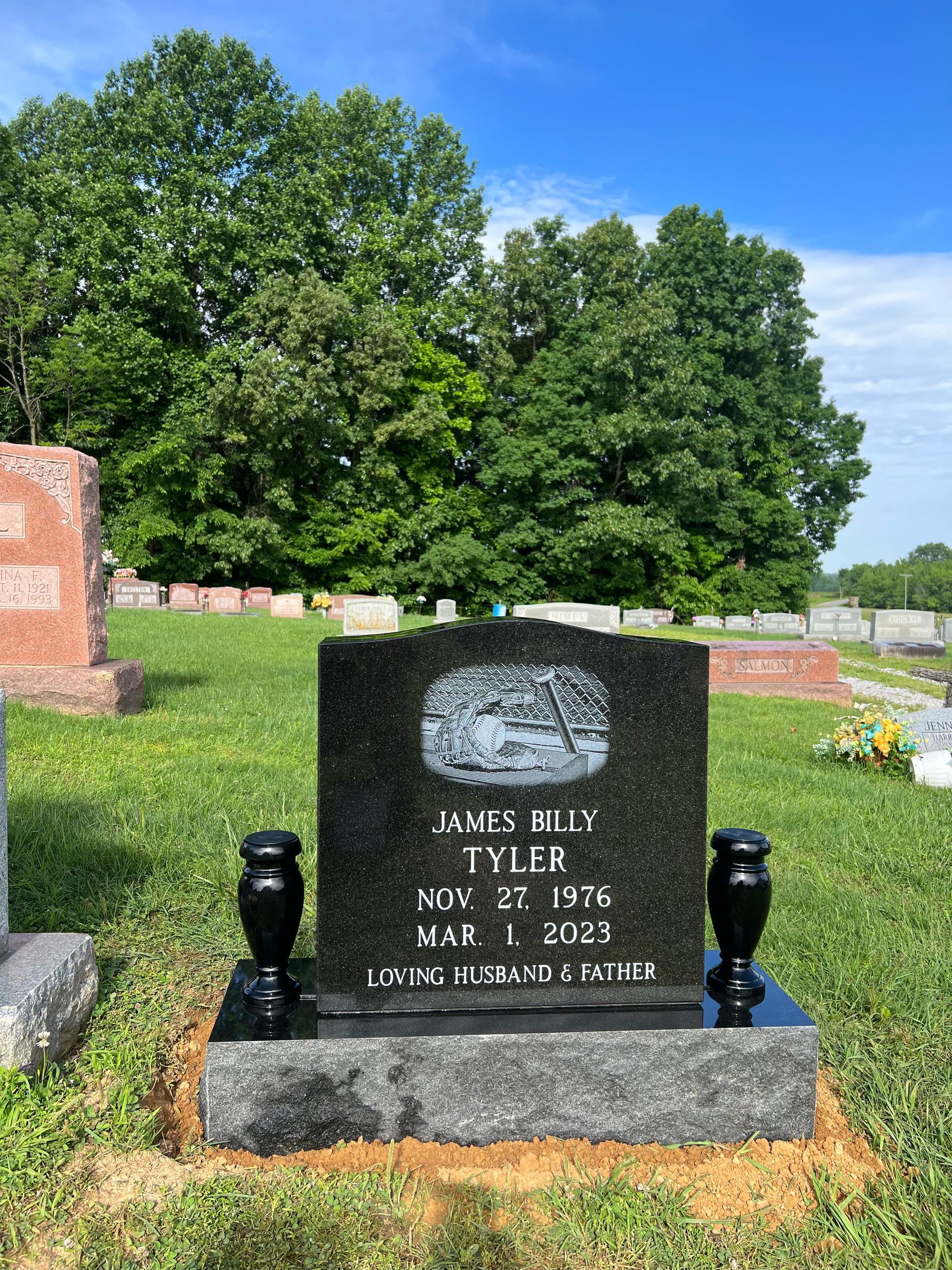 A gravestone in a cemetery with trees in the background.