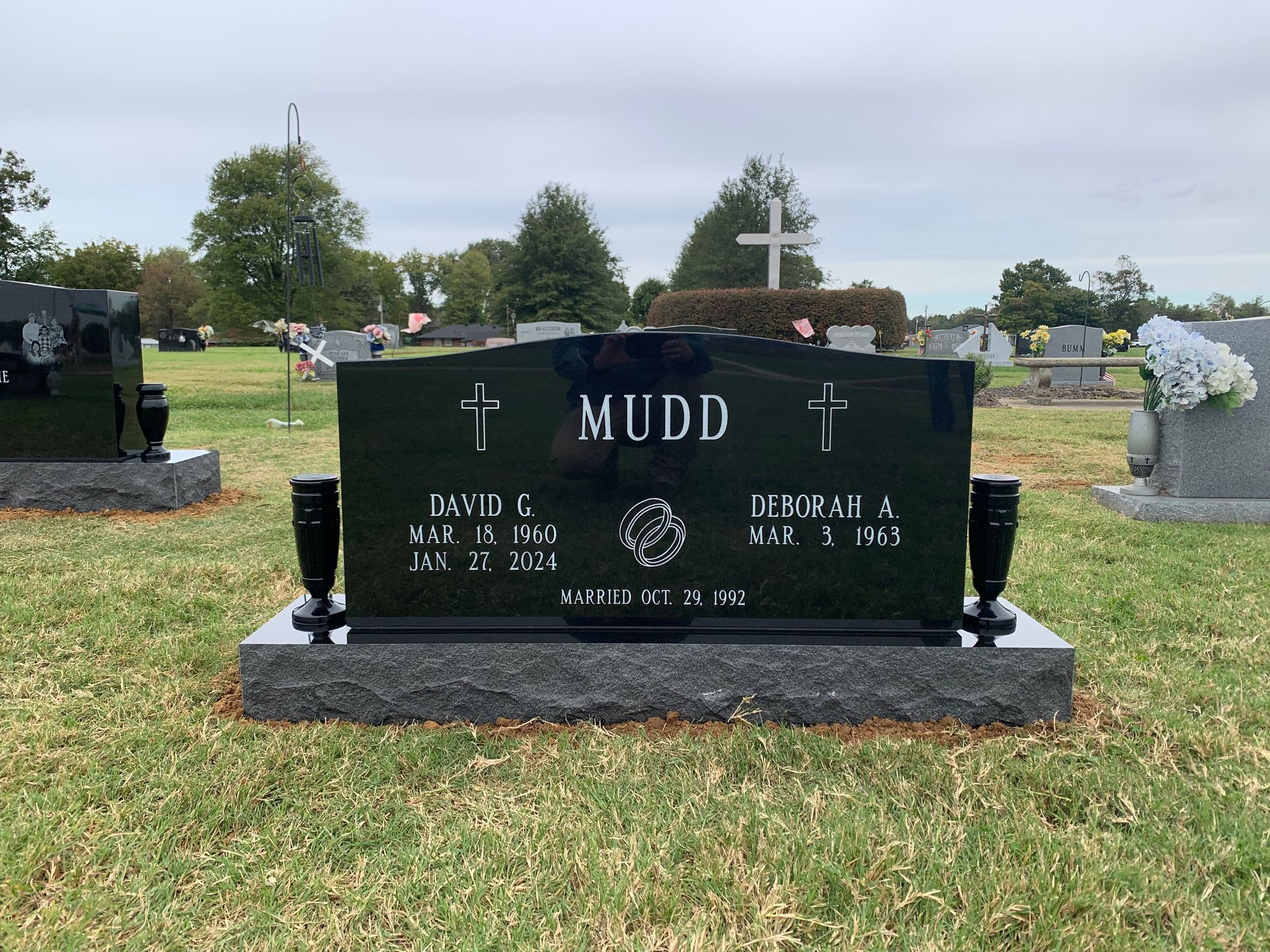 A black gravestone in a cemetery with the name mudd on it.