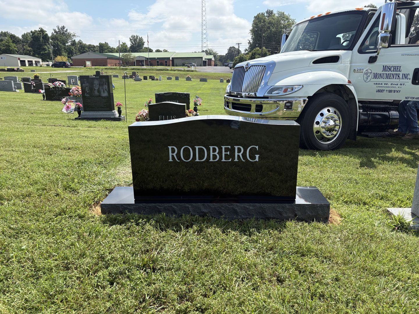 A black headstone in a cemetery reads 