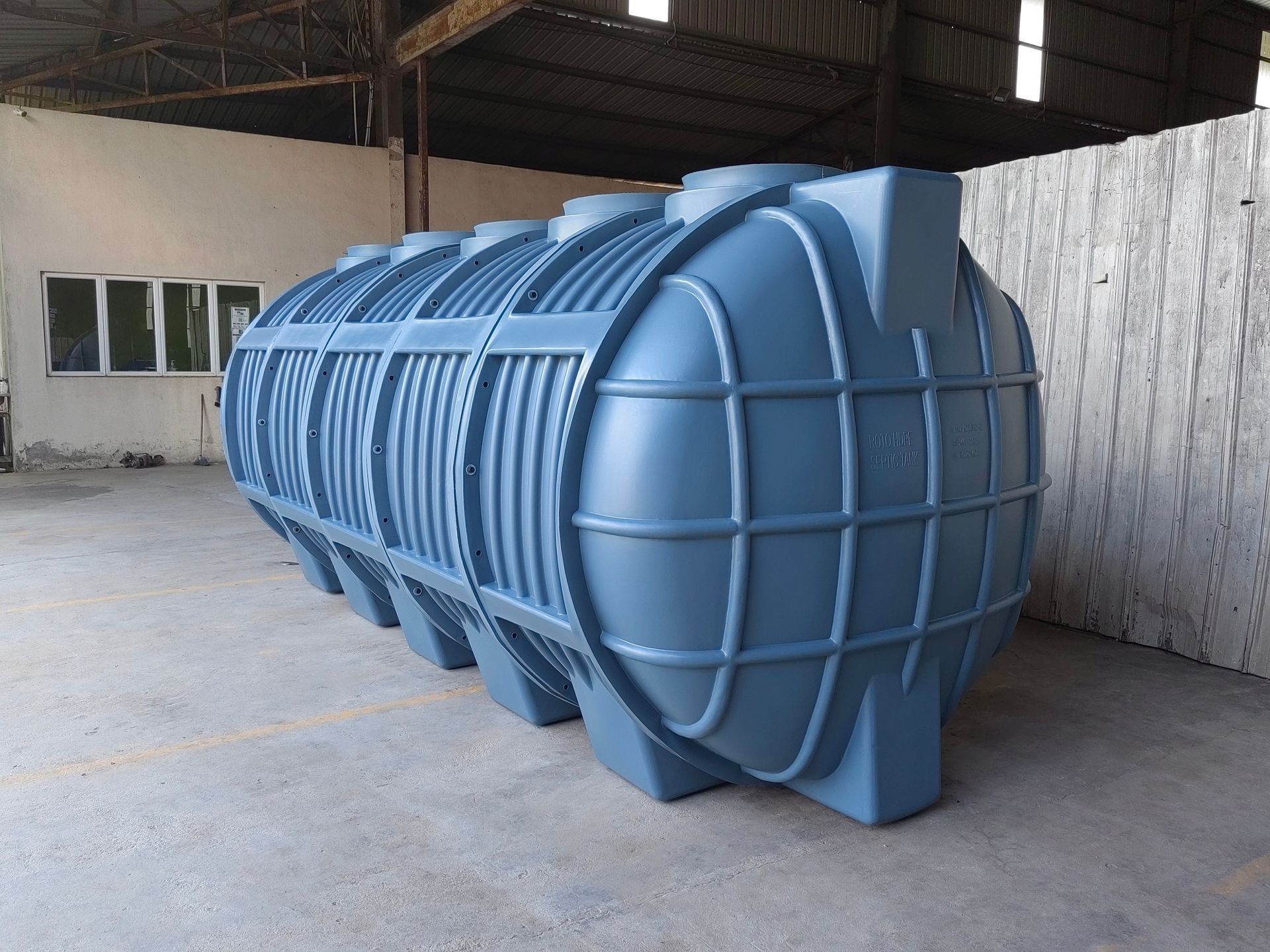 Blue, large, ribbed plastic septic tank sitting on a concrete surface, in a warehouse.
