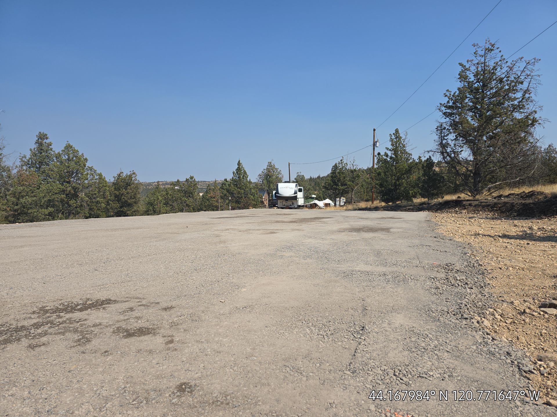 Yellow excavator demolishing a building, kicking up dust; debris covers the ground.