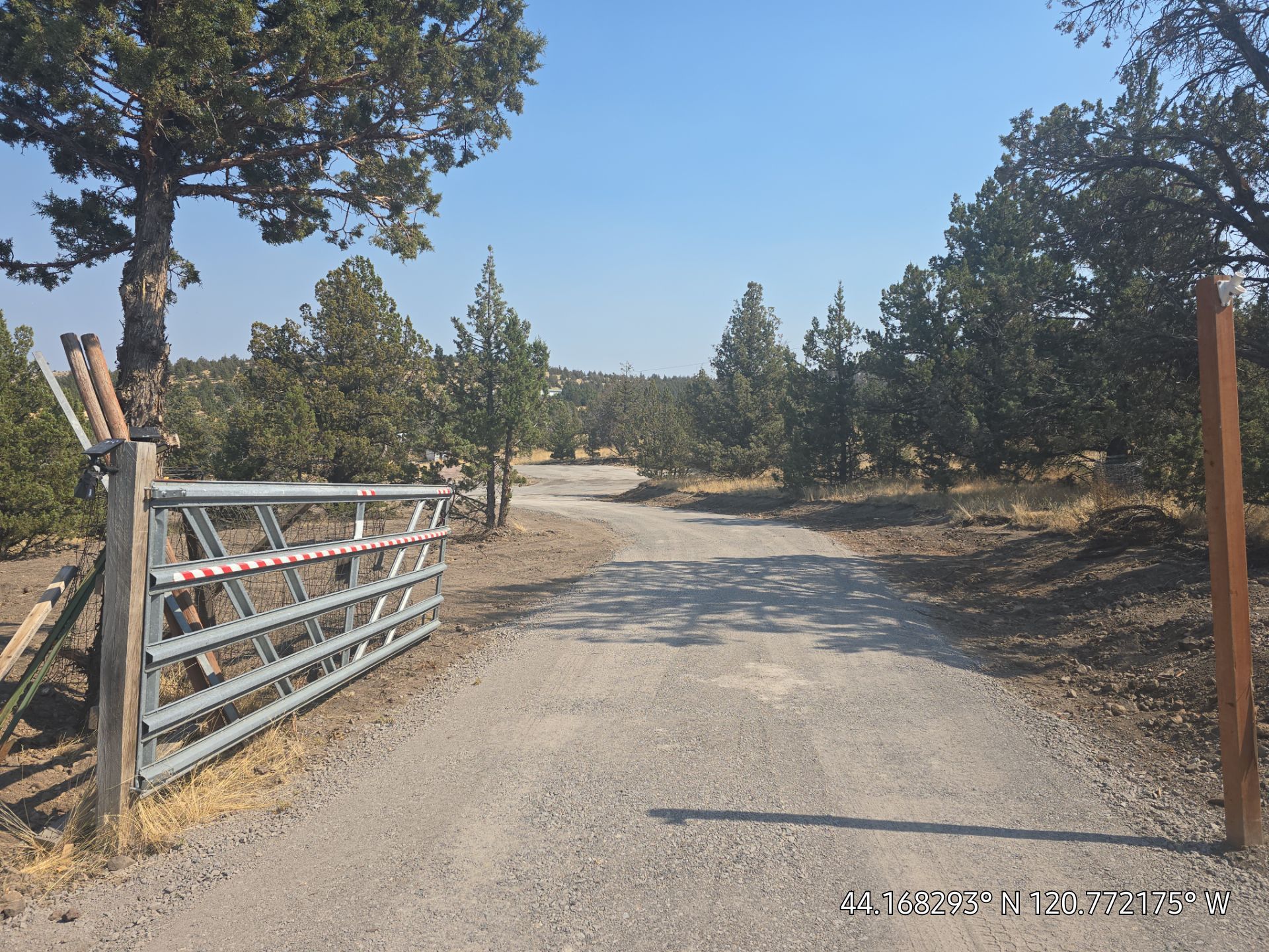 Construction worker using a compactor on a gravel surface near new houses. Orange work clothes and boots.