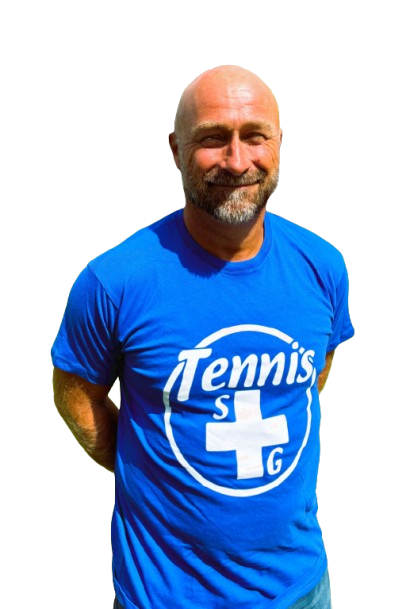 Un uomo con una maglietta da tennis blu e il logo sorride, con le braccia dietro la schiena.