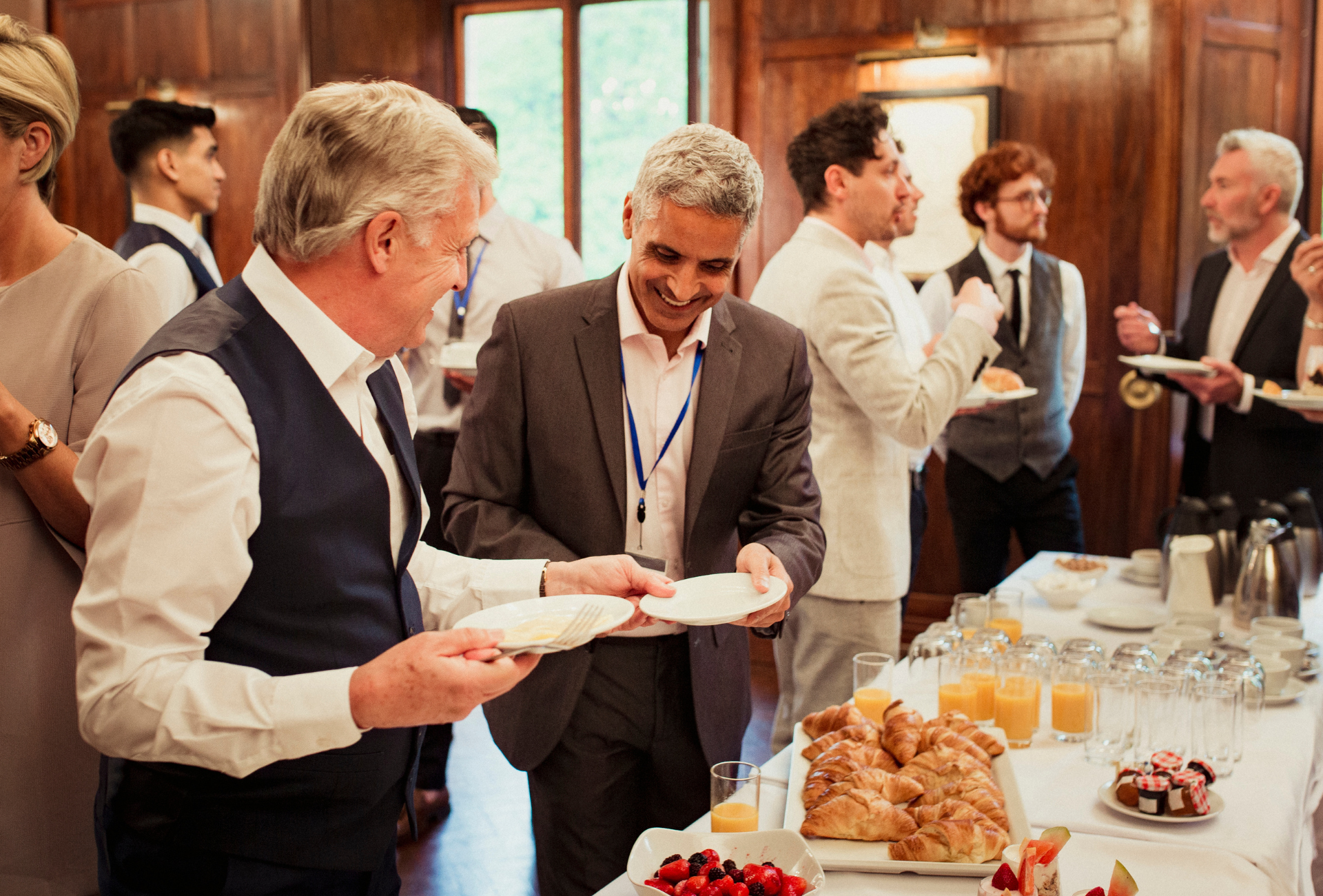 A group of people are standing around a buffet table eating food.