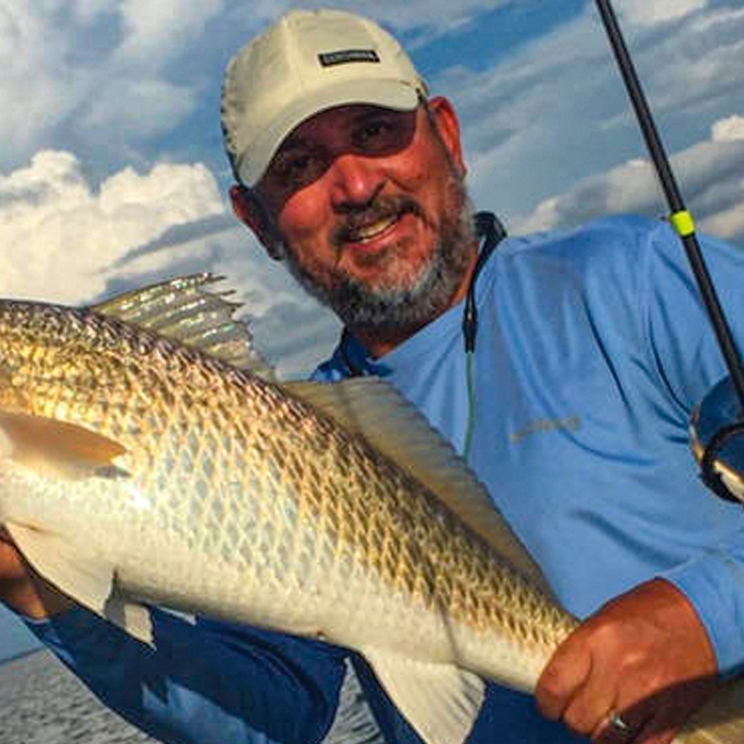 A man is holding a large fish in his hands.