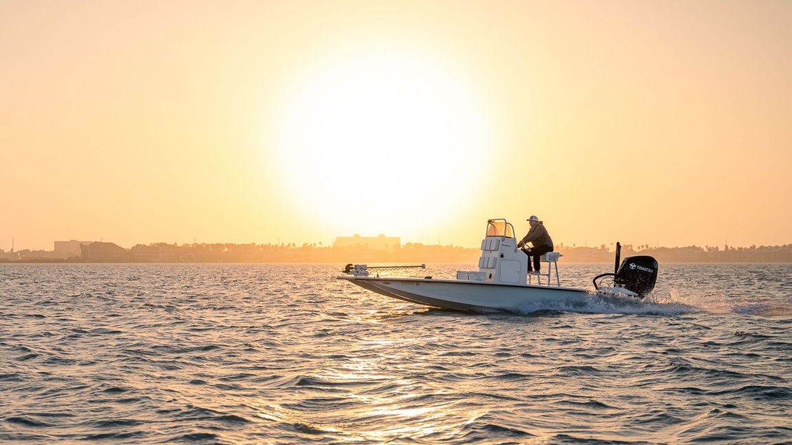 A boat is floating on top of a body of water at sunset.