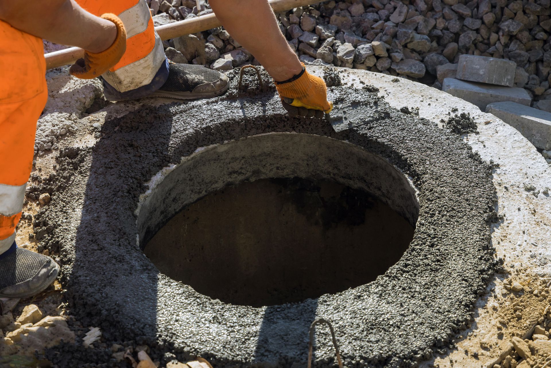 A man is pouring concrete into a manhole cover.