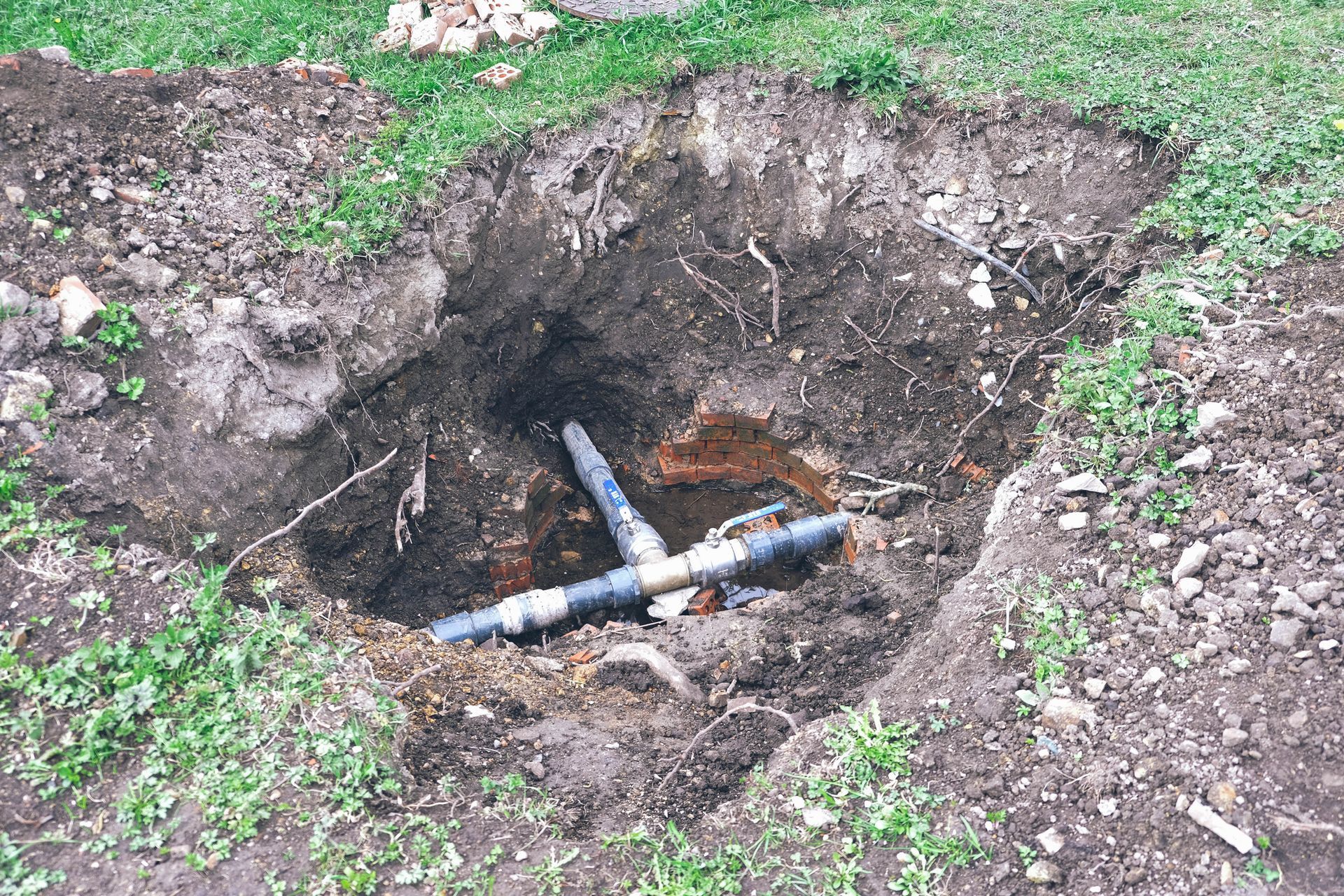 A blue pipe is laying in a hole in the ground.