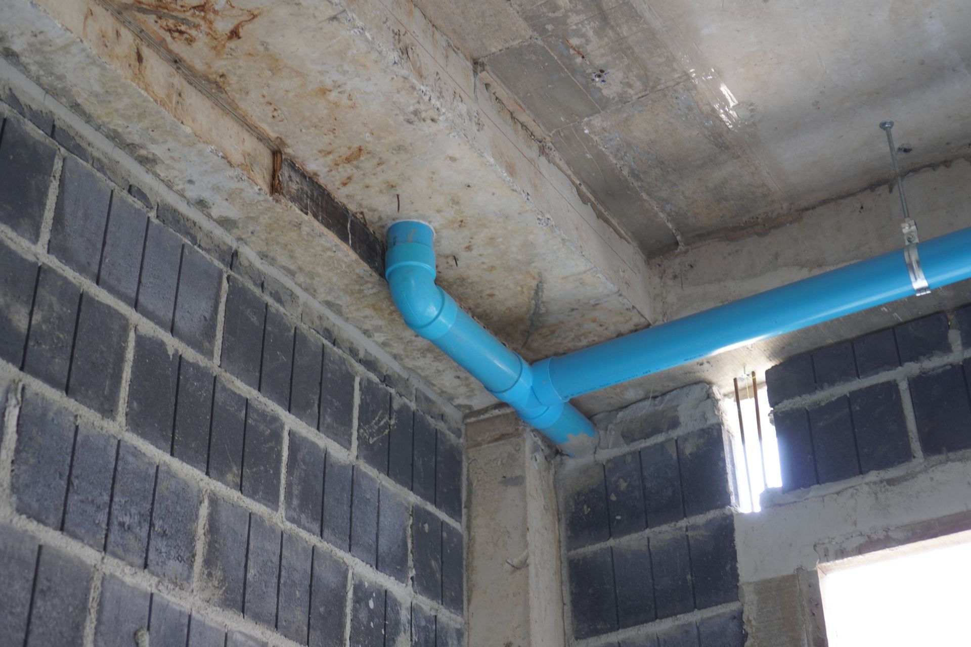 A blue pipe is hanging from the ceiling of a building.